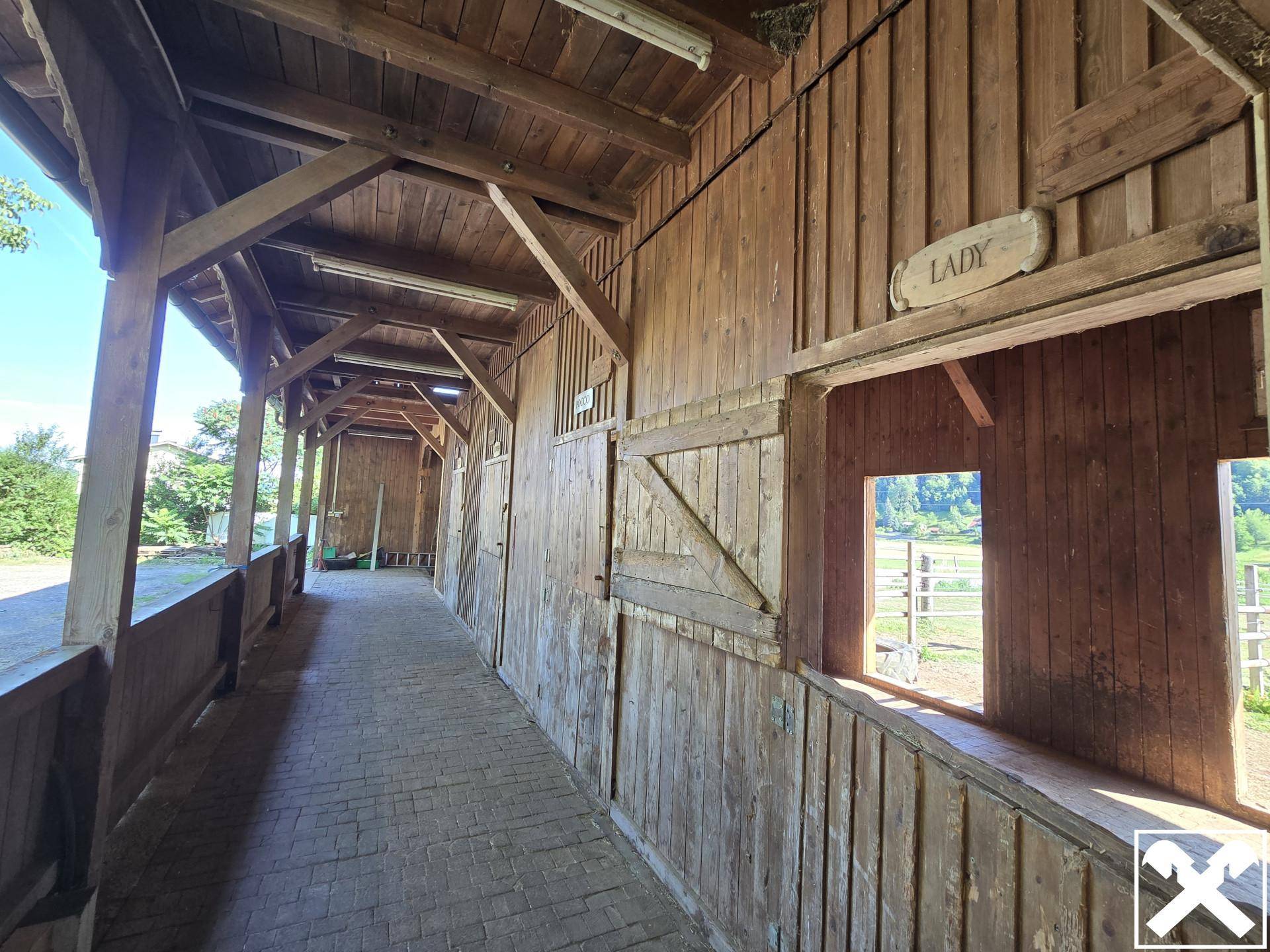 Überdachter Gang in der Holzscheune mit Blick auf die umliegende Landschaft.