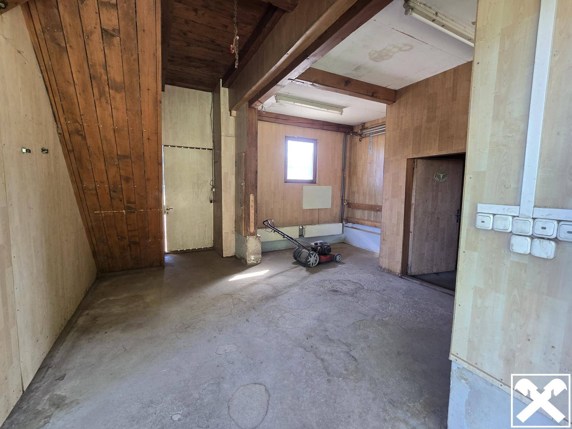 Geräumiger Abstellraum oder Werkstatt mit Betonboden und Holzwänden.