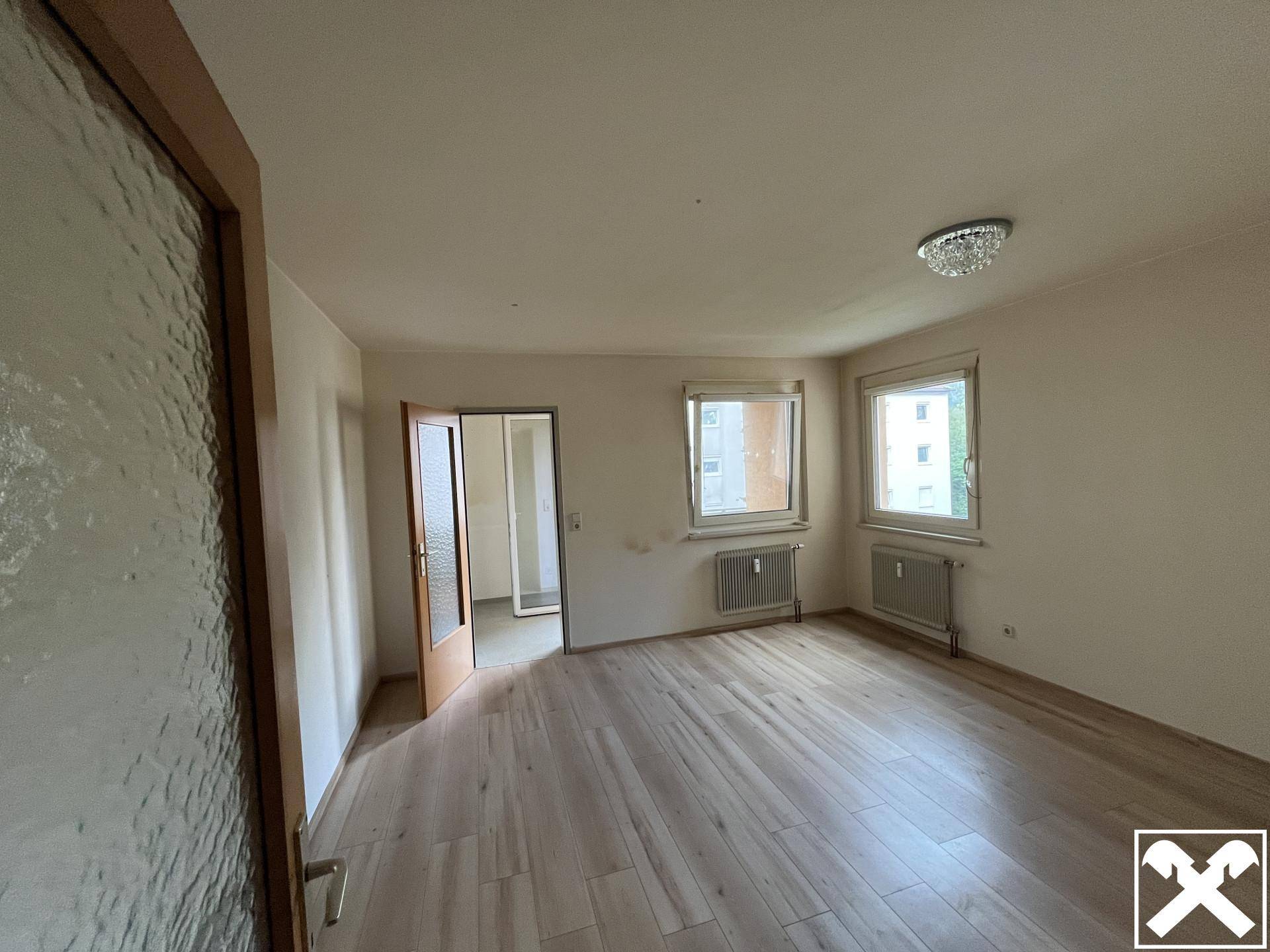 Geräumiges Zimmer mit hellem Laminatboden und zwei Fenstern für viel Tageslicht und Ausblick.