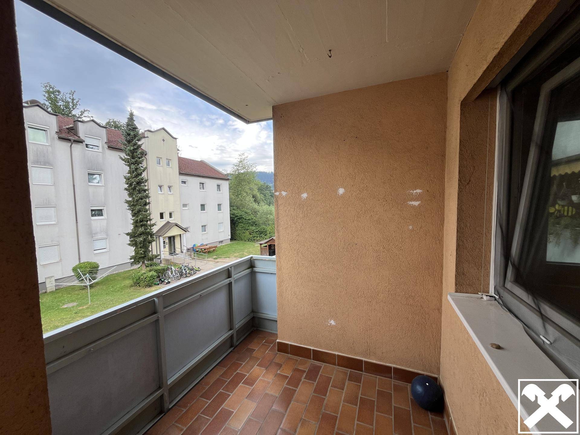 Balkon mit Terrakottafliesen und Blick auf die grüne Umgebung und andere Gebäude, ideal zum Entspannen.