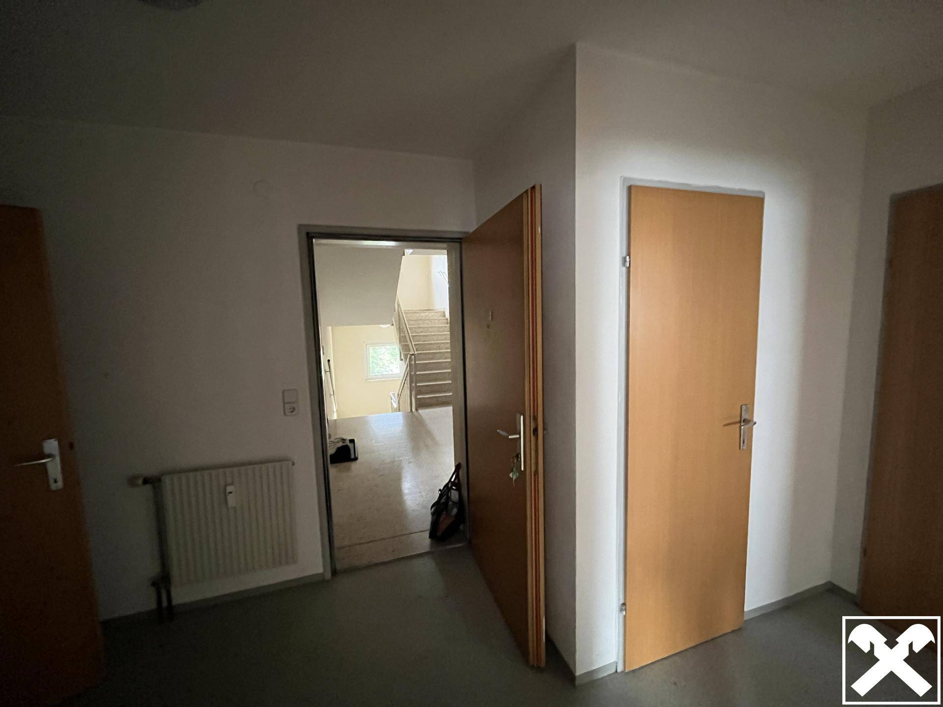 Heller Eingangsbereich mit mehreren Türen und Blick auf das Treppenhaus des Gebäudes, gut gepflegt.