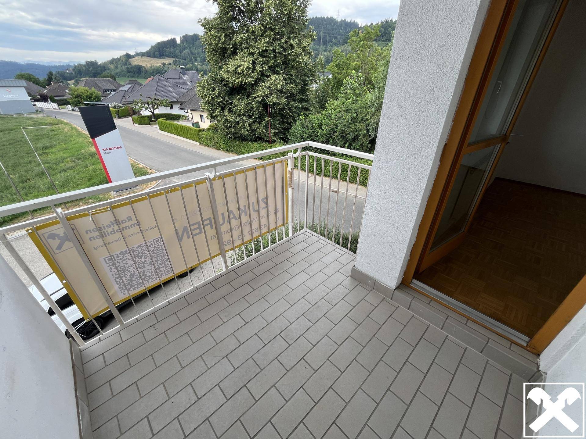 Kleiner Balkon mit Fliesenboden und Blick auf die Straße und umliegende Häuser.