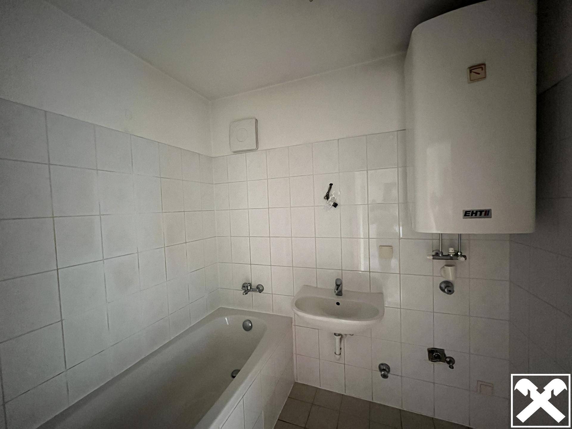Badezimmer mit Badewanne, Waschbecken und weißen Wandfliesen.