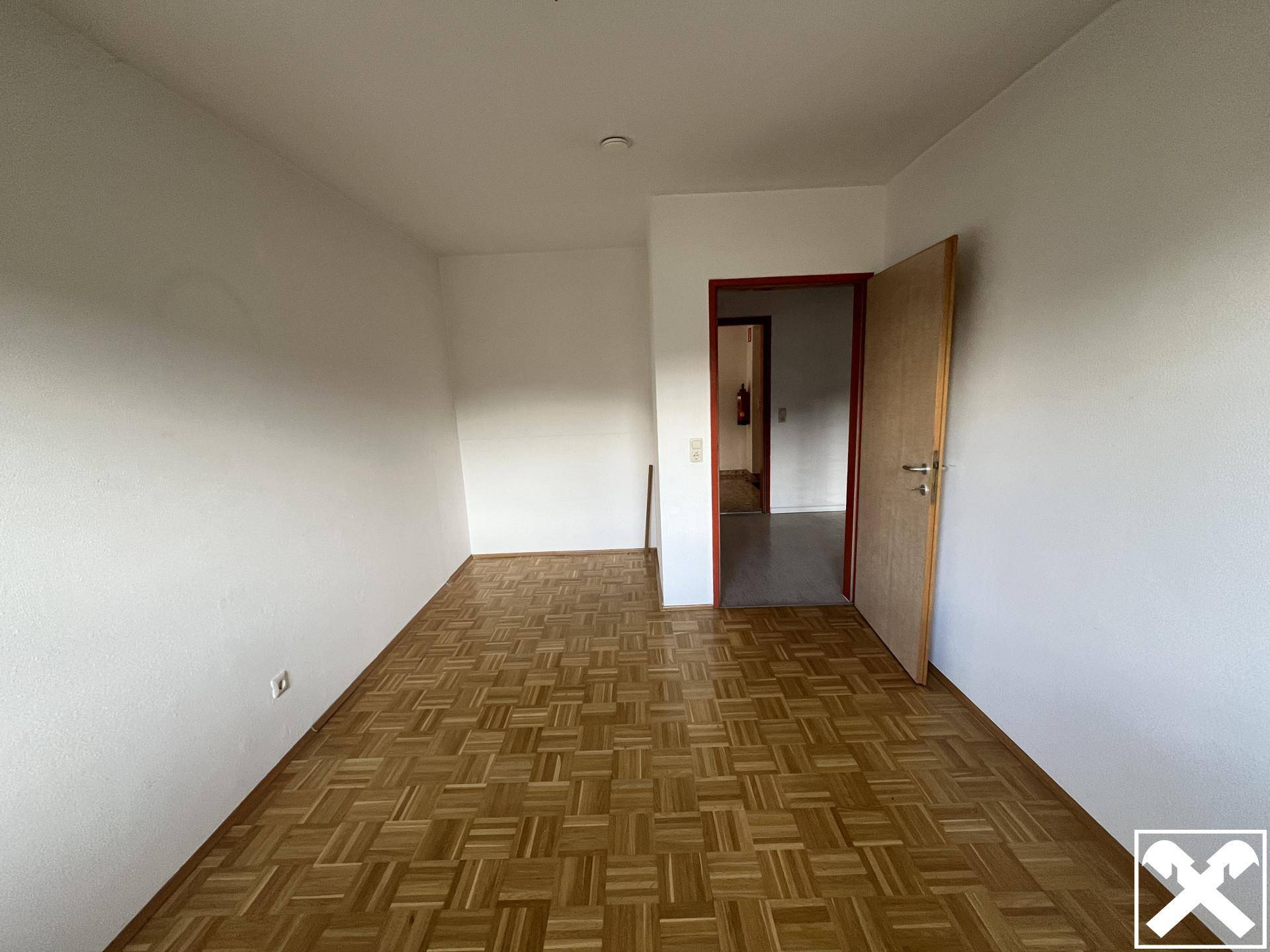 Geräumiges Zimmer mit Parkettboden und Zugang zu einem weiteren Bereich.