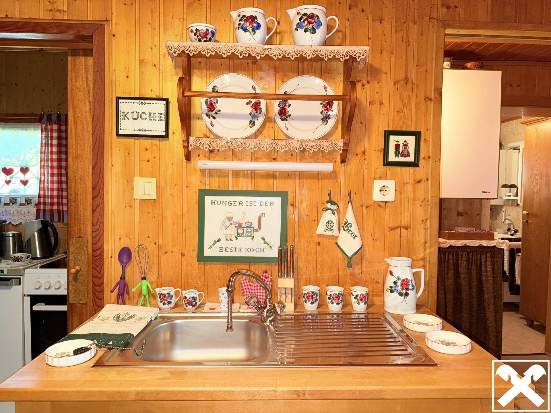 Rustikale Küche mit Holztheke, Spüle und traditionellen Dekorationen an den Holzvertäfelungen.