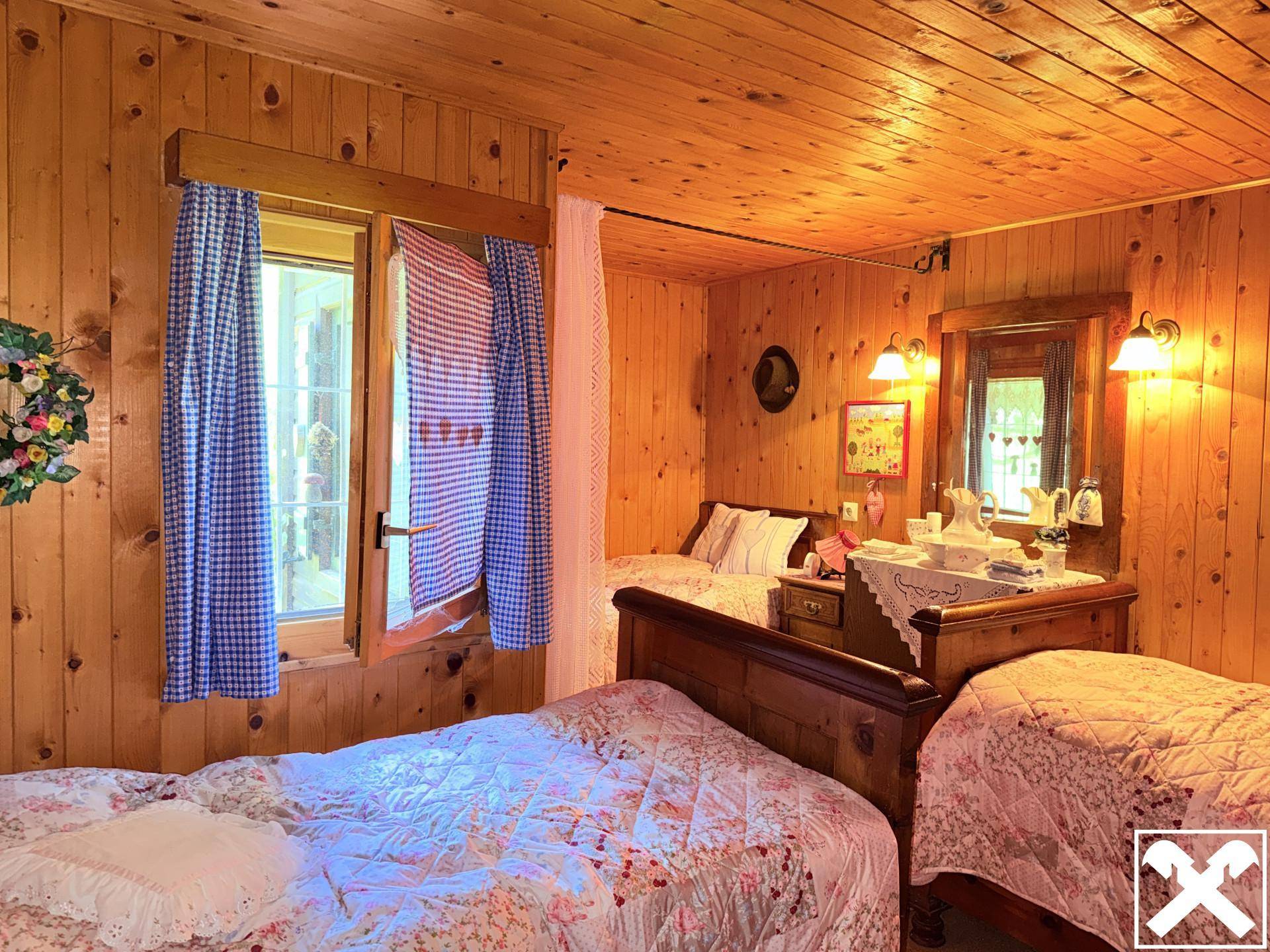 Schlafzimmer im Landhausstil mit Holzvertäfelung, zwei Betten und traditioneller Einrichtung.