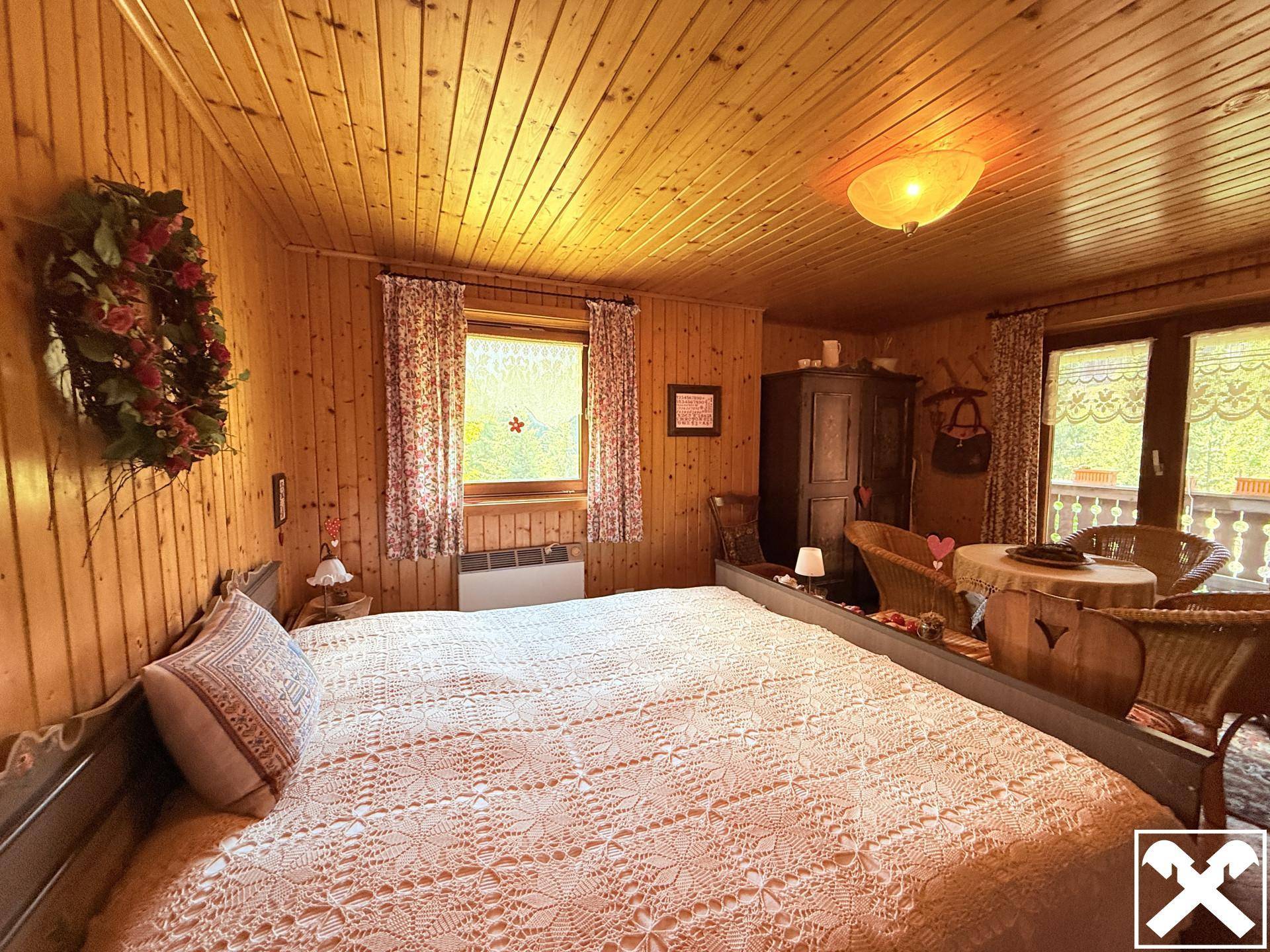 Gemütliches Schlafzimmer mit großem Bett, Holzvertäfelung und Zugang zu einem Balkon.