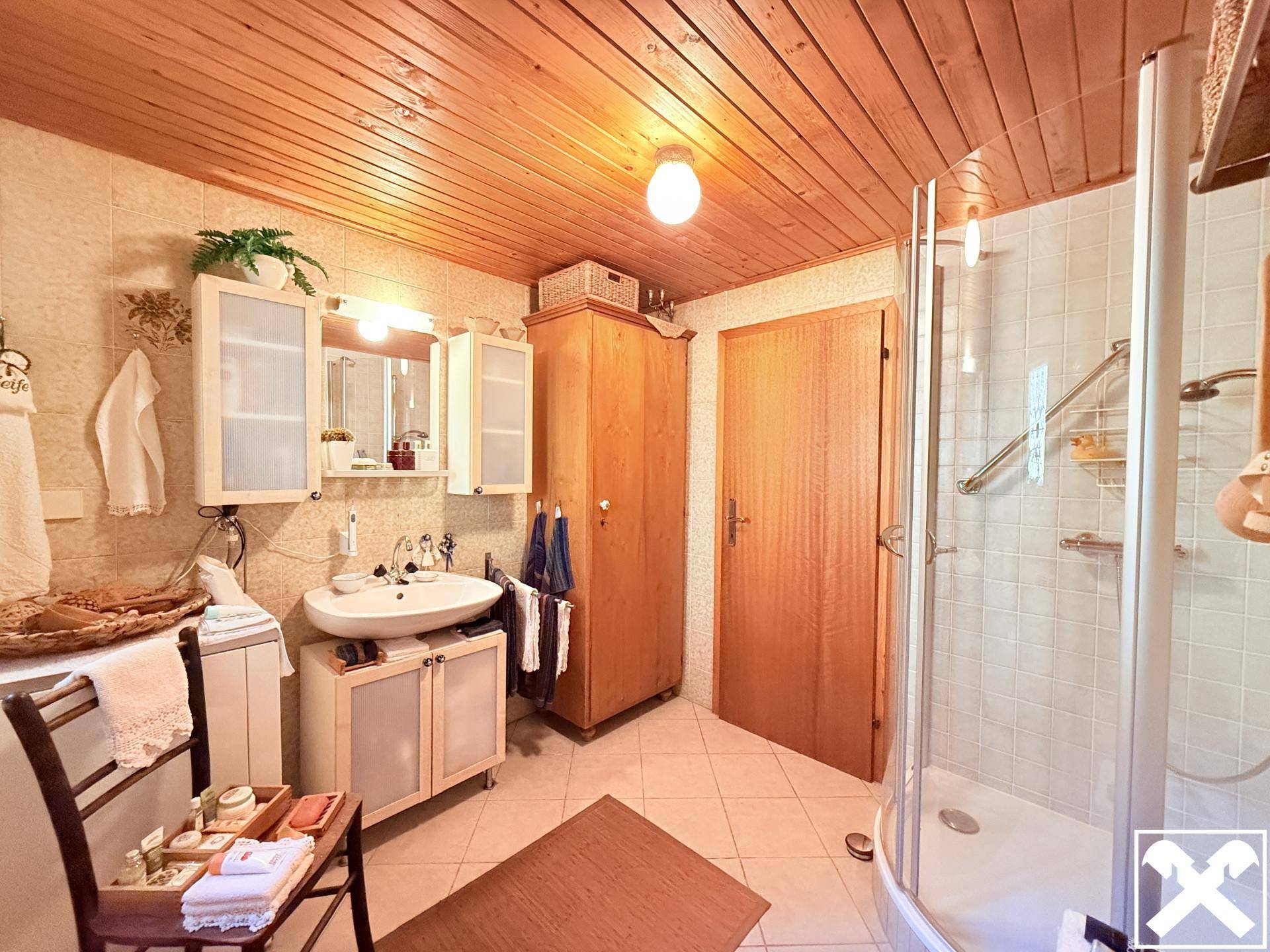 Badezimmer mit Duschkabine, Waschbecken und Holzdecke im traditionellen Stil.