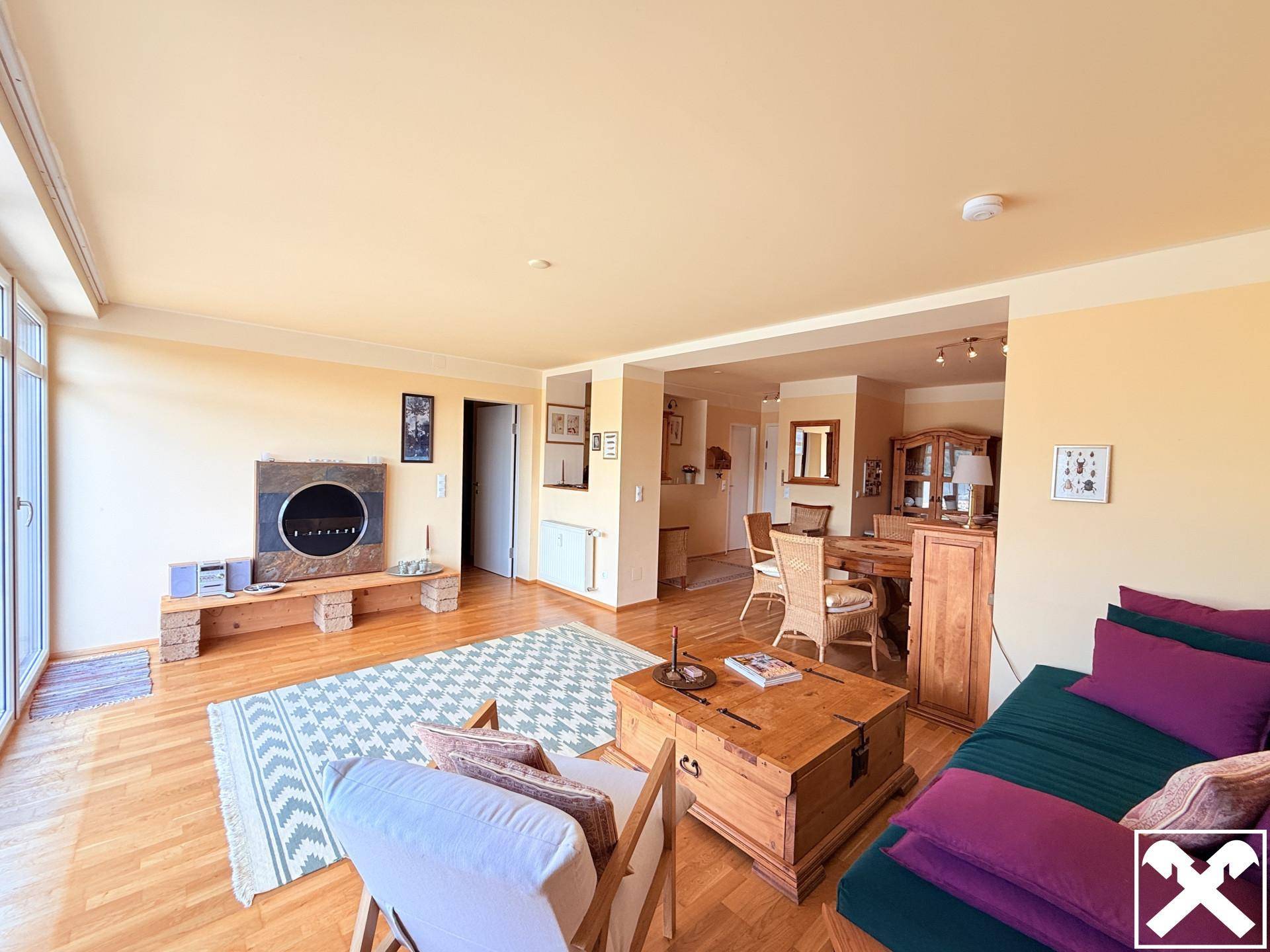 Heller Wohn- und Essbereich mit Parkettboden, gemütlichem Sofa und modernem Kamin, ideal für gesellige Stunden.