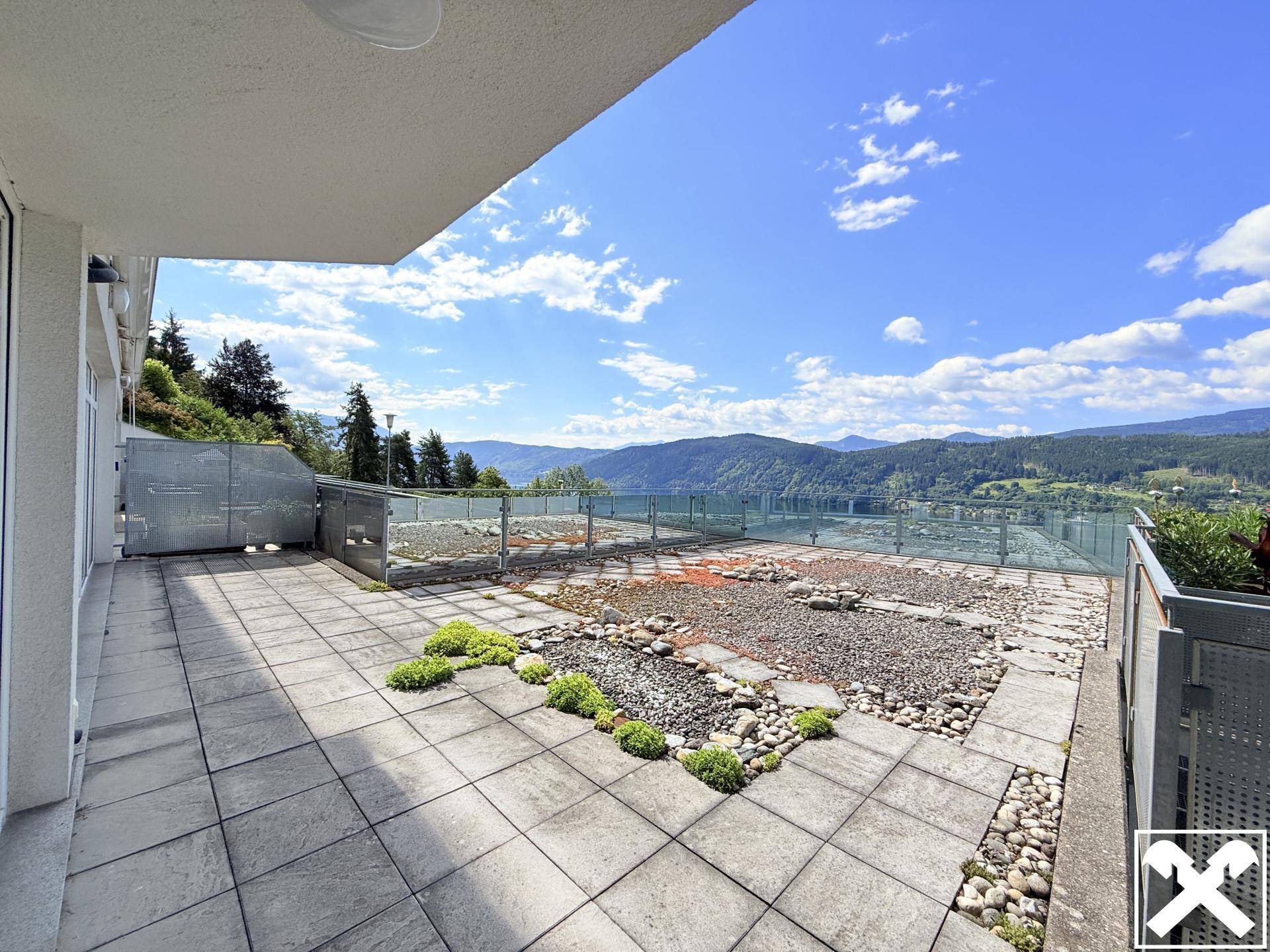 Geräumige Terrasse mit Fliesenboden und dekorativen Steinen, bietet einen weiten Blick auf den See und die Berge.