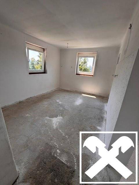 Leerer Raum mit Betonboden und weißen Wänden, bereit für die Renovierung.