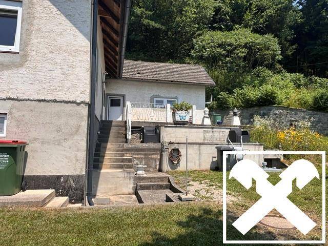 Seitlicher Zugang zum Haus mit Betontreppe und kleiner erhöhter Terrasse.