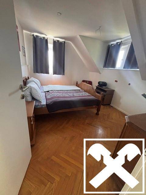 Gemütliches Schlafzimmer mit Holzbett, Parkettboden und schrägen Wänden im Dachgeschoss.