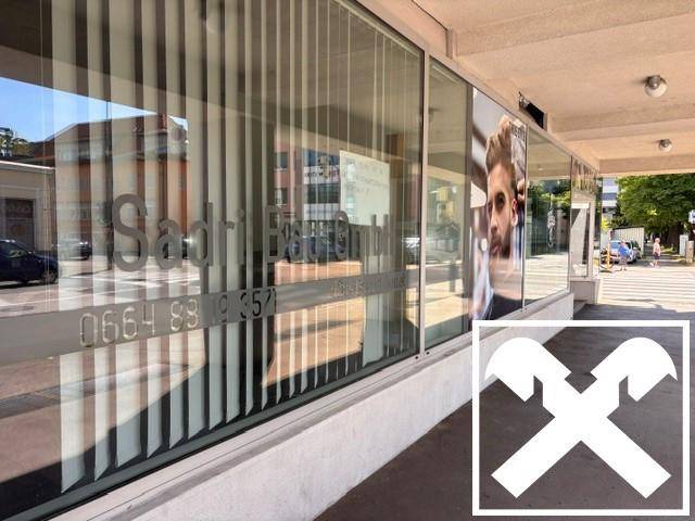 Nahaufnahme der Schaufenster im Erdgeschoss mit reflektierenden Oberflächen und vertikalen Jalousien.