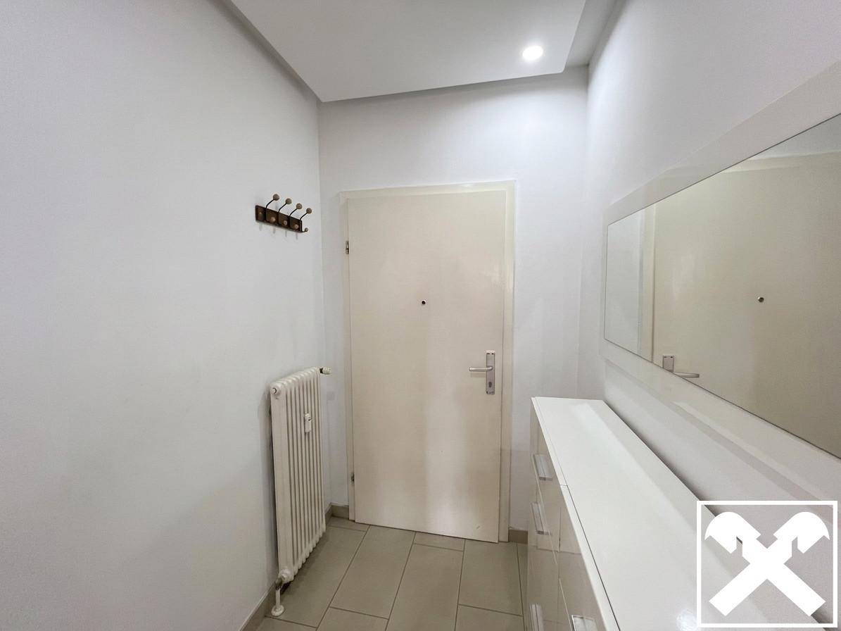 Eingangsbereich mit Haustür, Heizkörper, Garderobe, Konsole mit Spiegel und Fliesenboden.