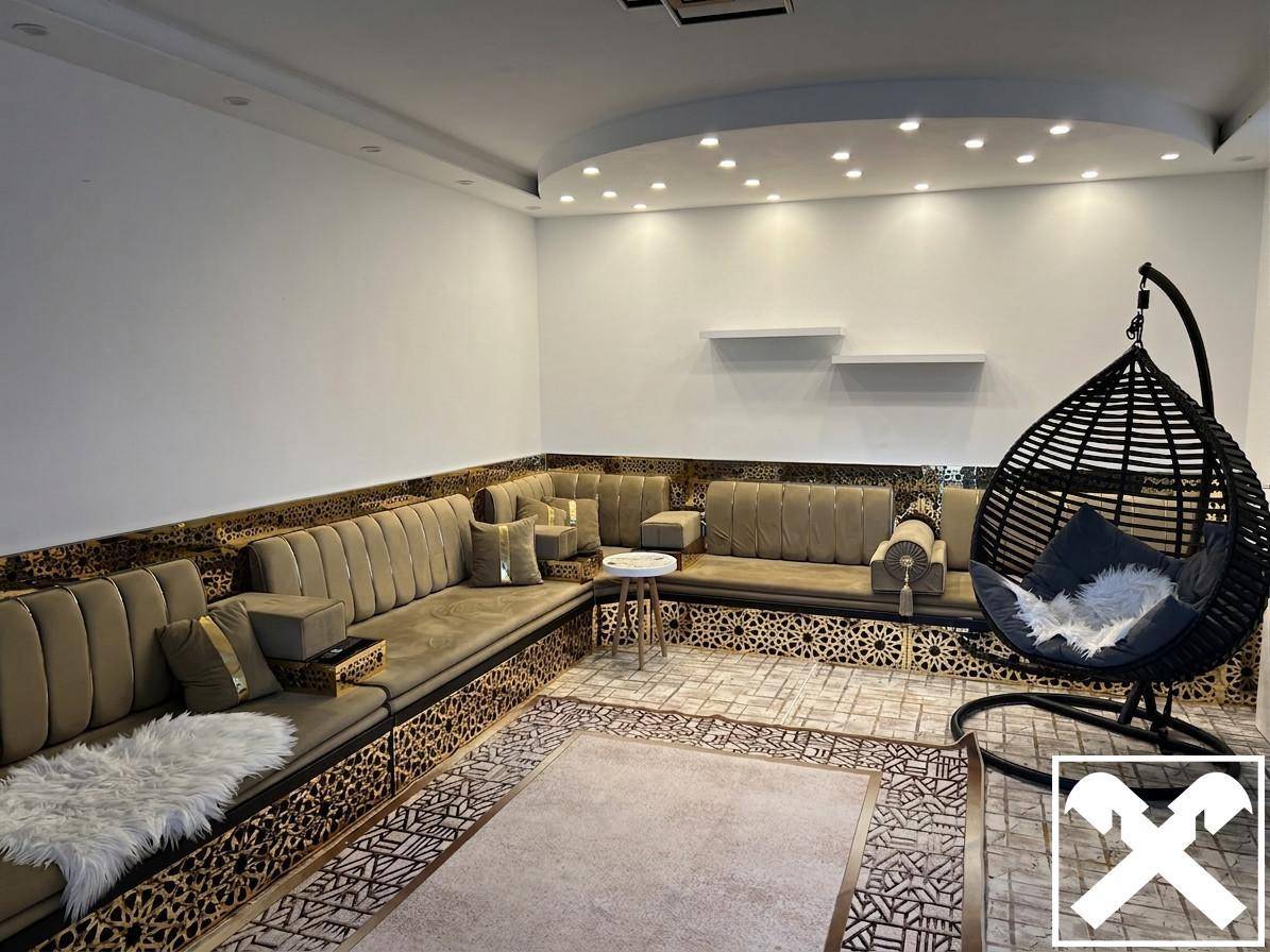 Geräumiges Wohnzimmer mit bequemer U-förmiger Sitzgruppe, Hängesessel und moderner Deckenbeleuchtung.