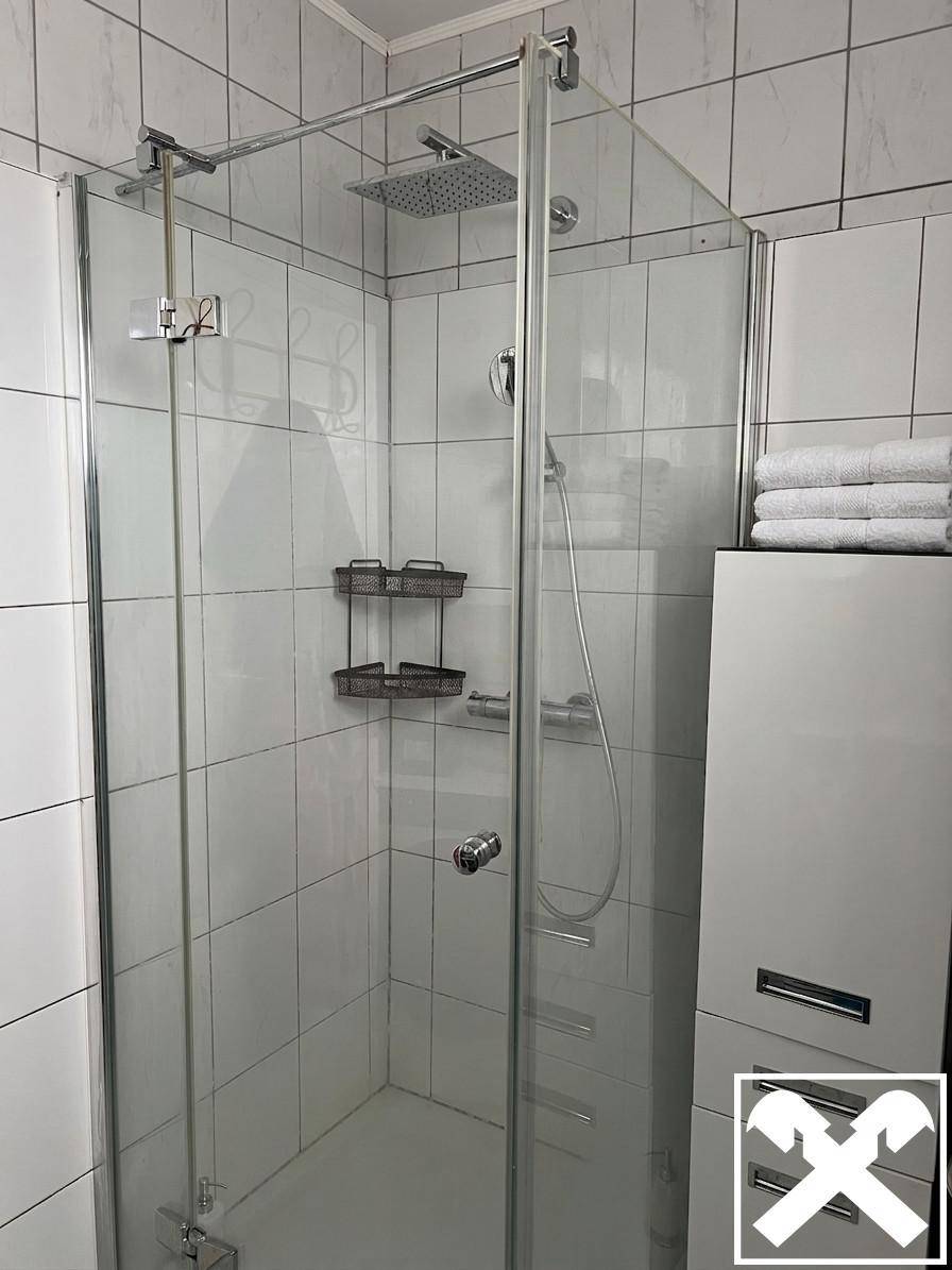 Modernes Badezimmer mit Glasduschkabine, Regendusche und weißen Fliesen.