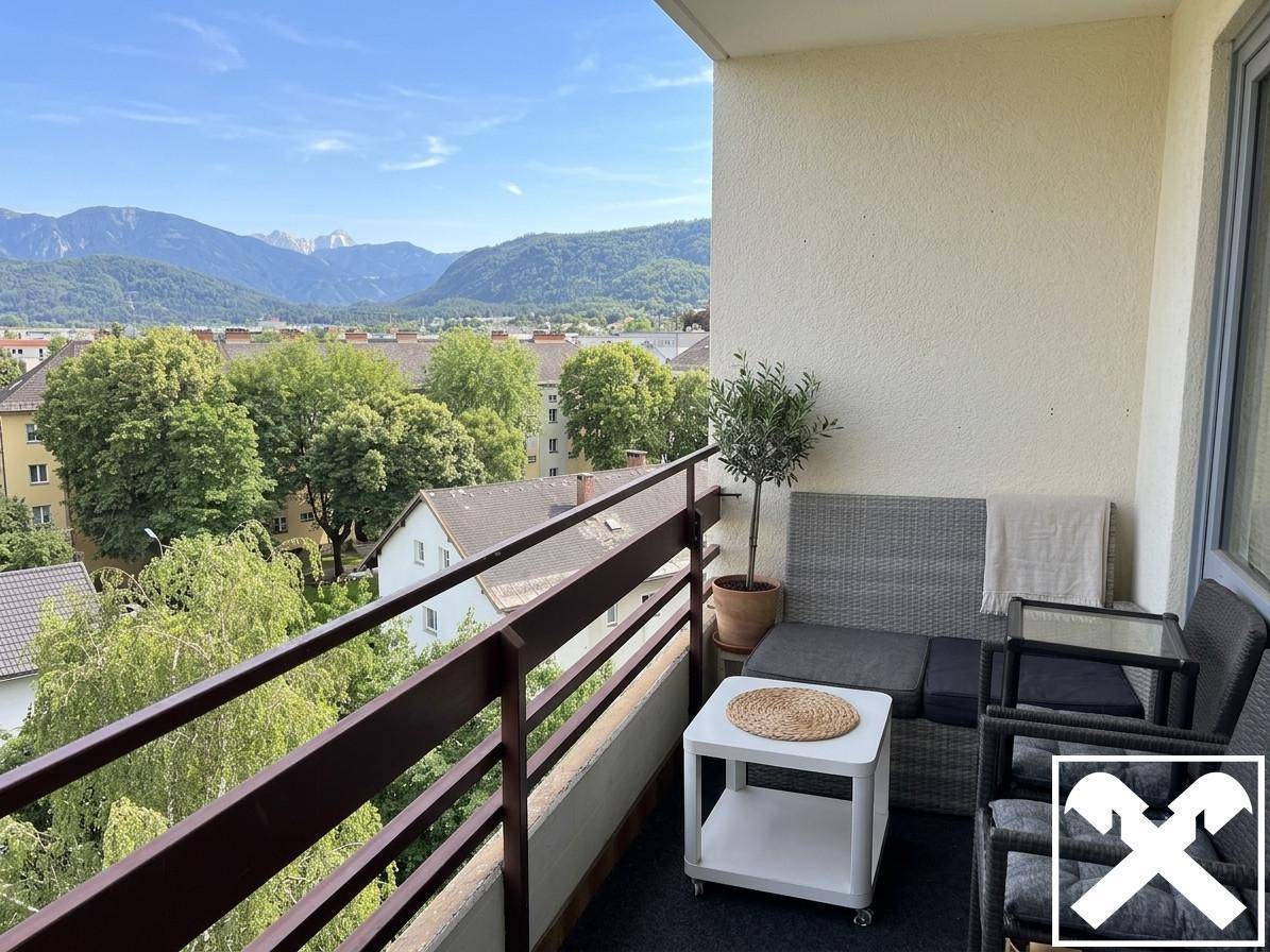 Möblierter Balkon mit Sitzgelegenheiten, Pflanzen und einem weiten Blick auf die Berge und Natur.