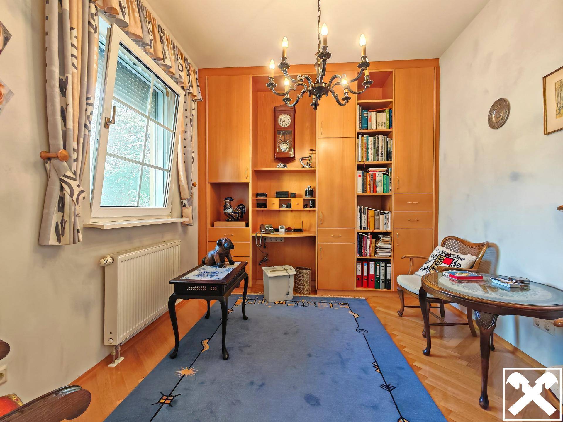 Arbeitszimmer mit Holzeinbauschränken, Schreibtisch und Parkettboden.