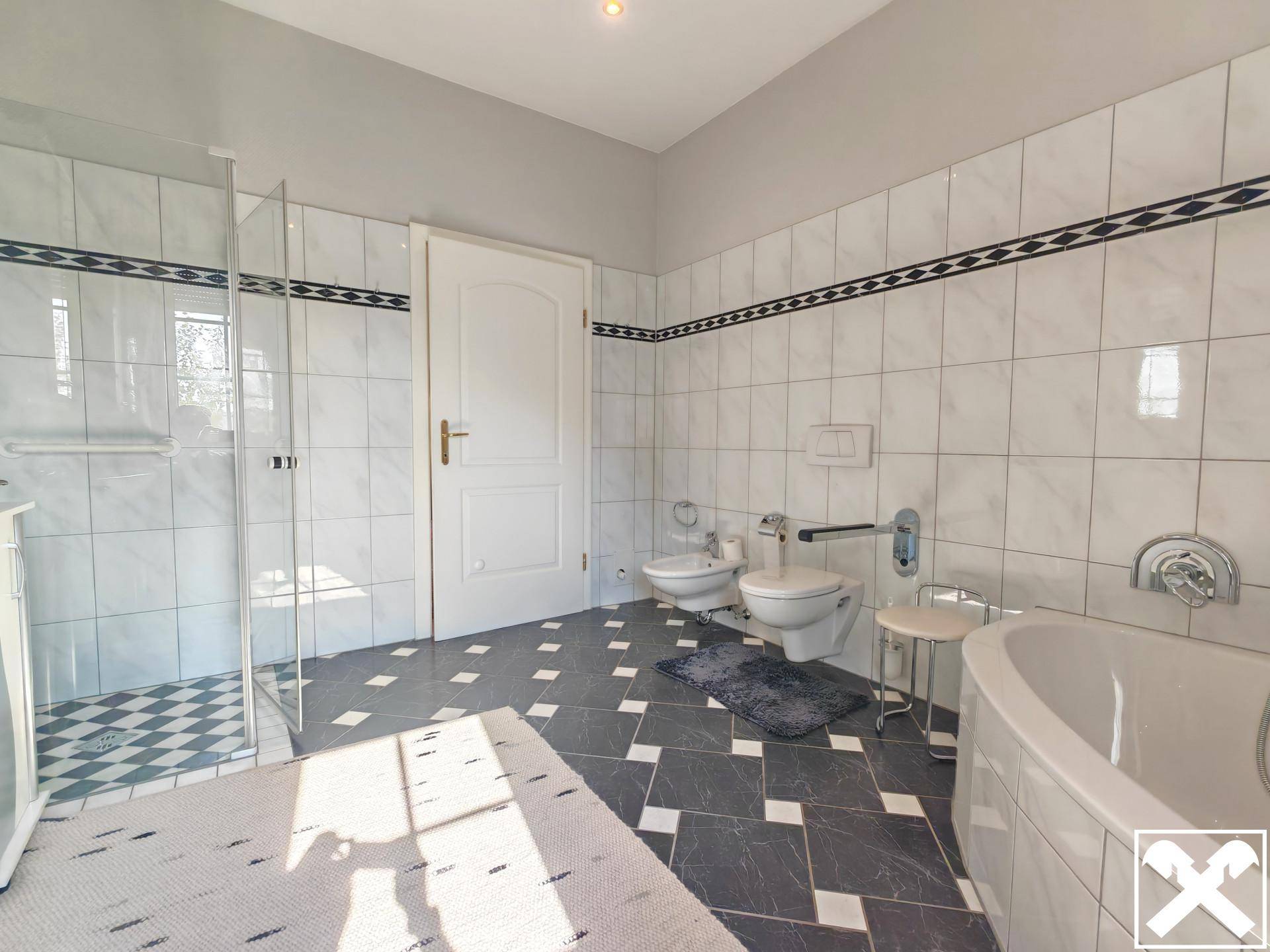 Helles Badezimmer mit Dusche, Badewanne, Bidet und Wand-WC.