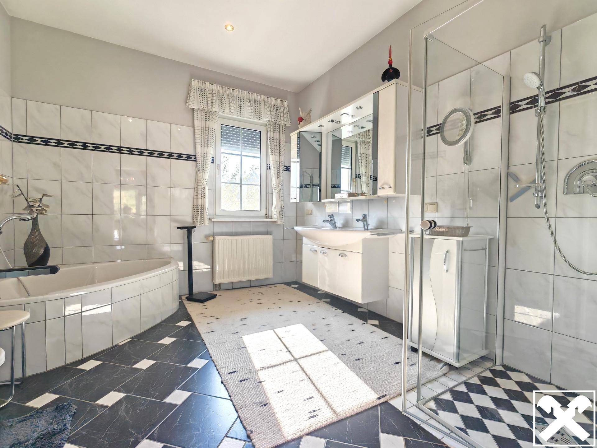 Geräumiges Badezimmer mit Badewanne, Dusche, Doppelwaschbecken und Fenster.