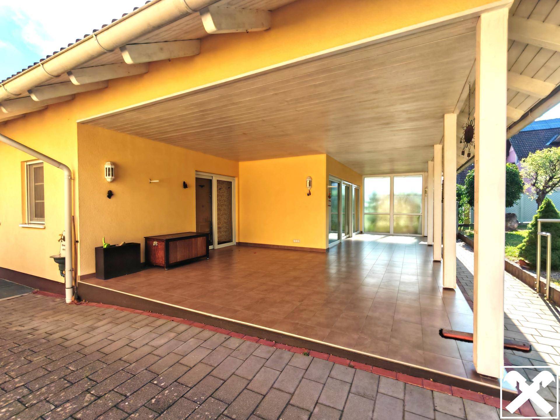 Überdachte Terrasse mit Fliesenboden und Zugang zum Innenbereich des Hauses.