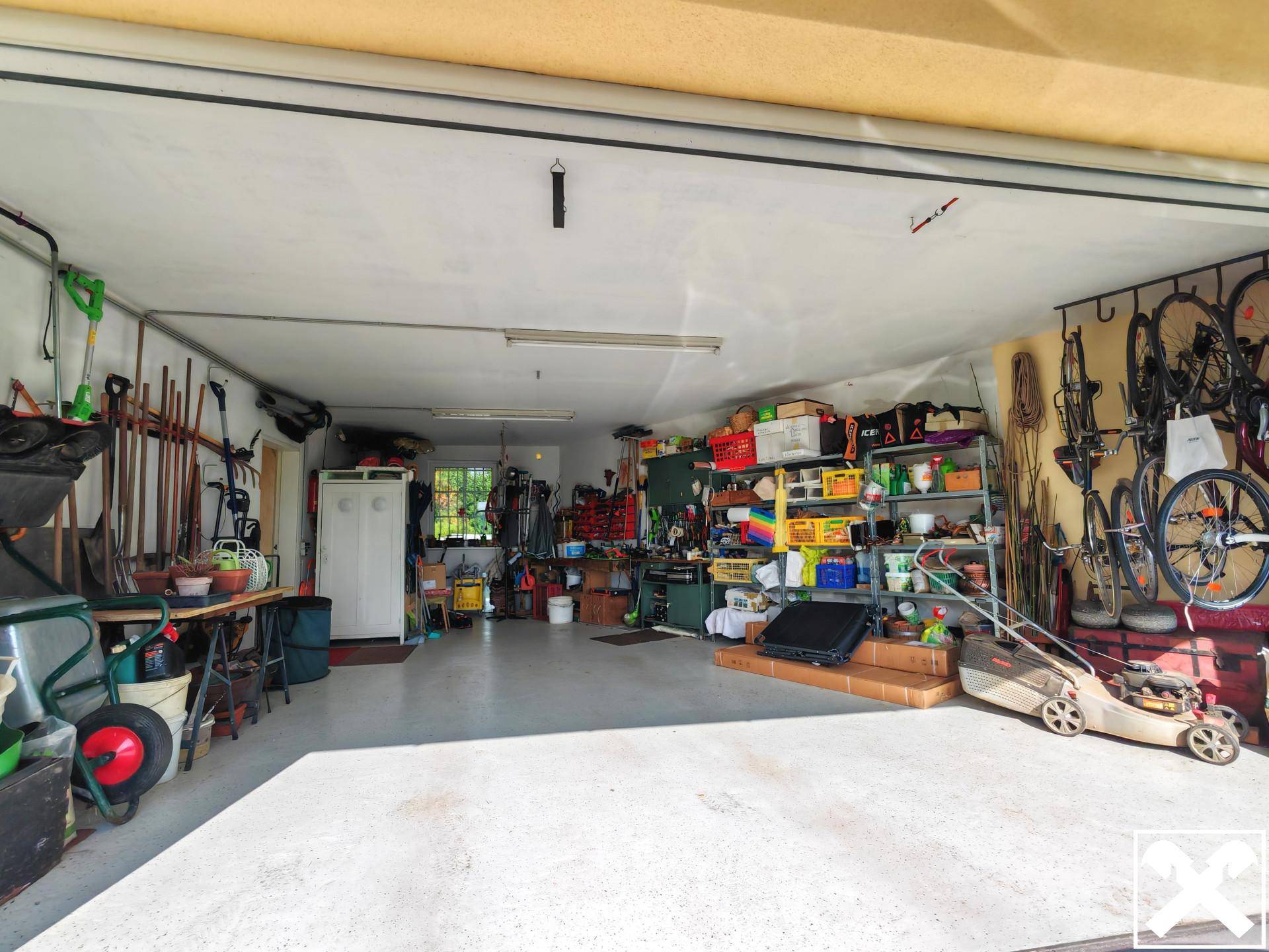 Geräumige Garage mit viel Stauraum, Werkzeugen und Gartengeräten.