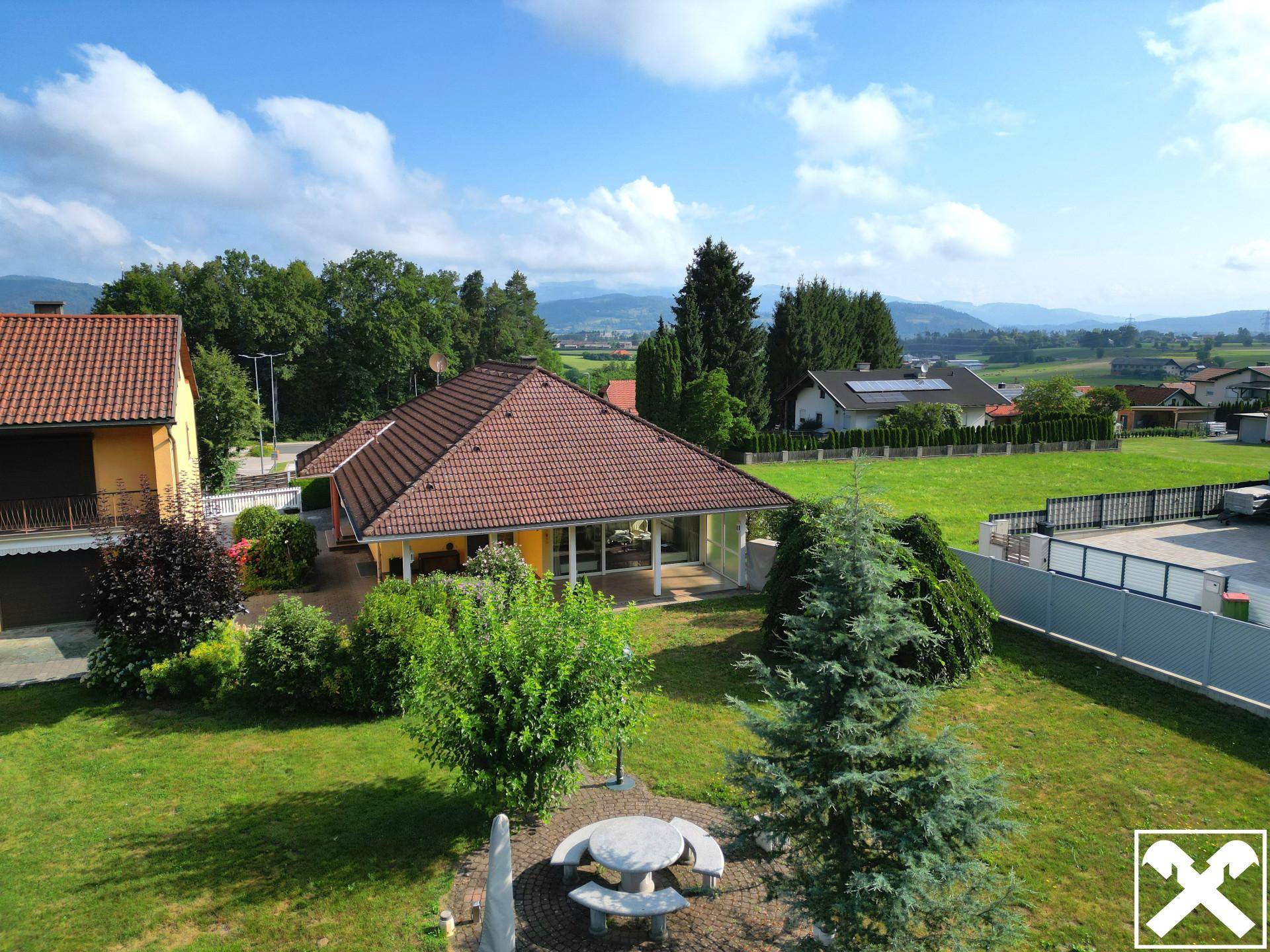 Weitläufiger Garten mit Sitzbereich und Blick auf die umliegende Landschaft und Berge.