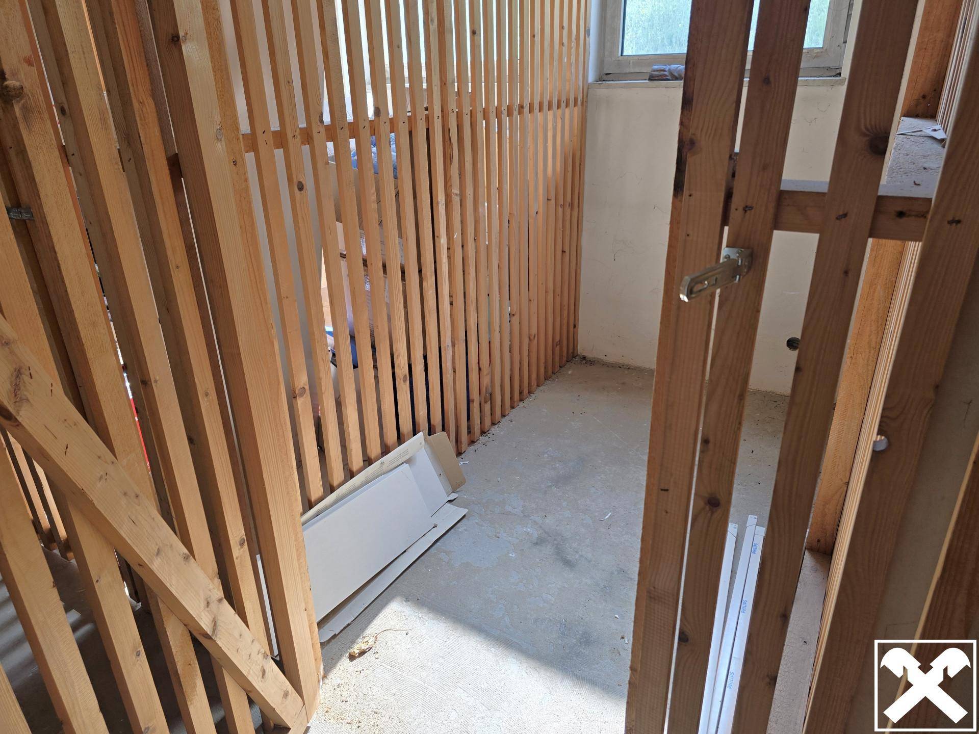 Kellerabteil mit Holzlattenwänden und Betonboden, ideal als Stauraum.
