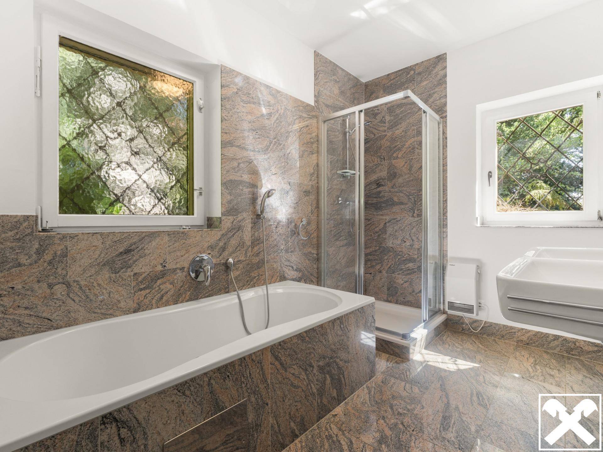 Modernes Badezimmer mit Badewanne, Duschkabine und zwei Fenstern für Tageslicht.