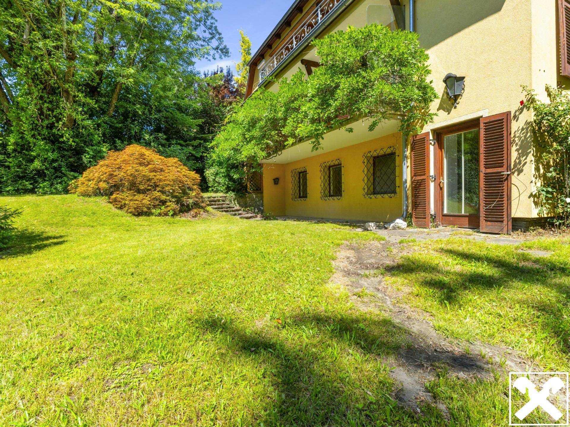 Sonnige Rasenfläche direkt am Haus mit Zugang zu einer überdachten Terrasse.