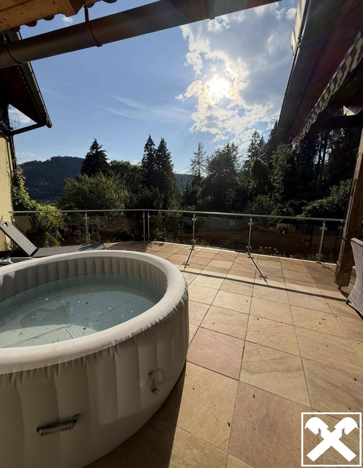 Sonniger Terrassenbereich mit aufblasbarem Whirlpool und Bergblick.