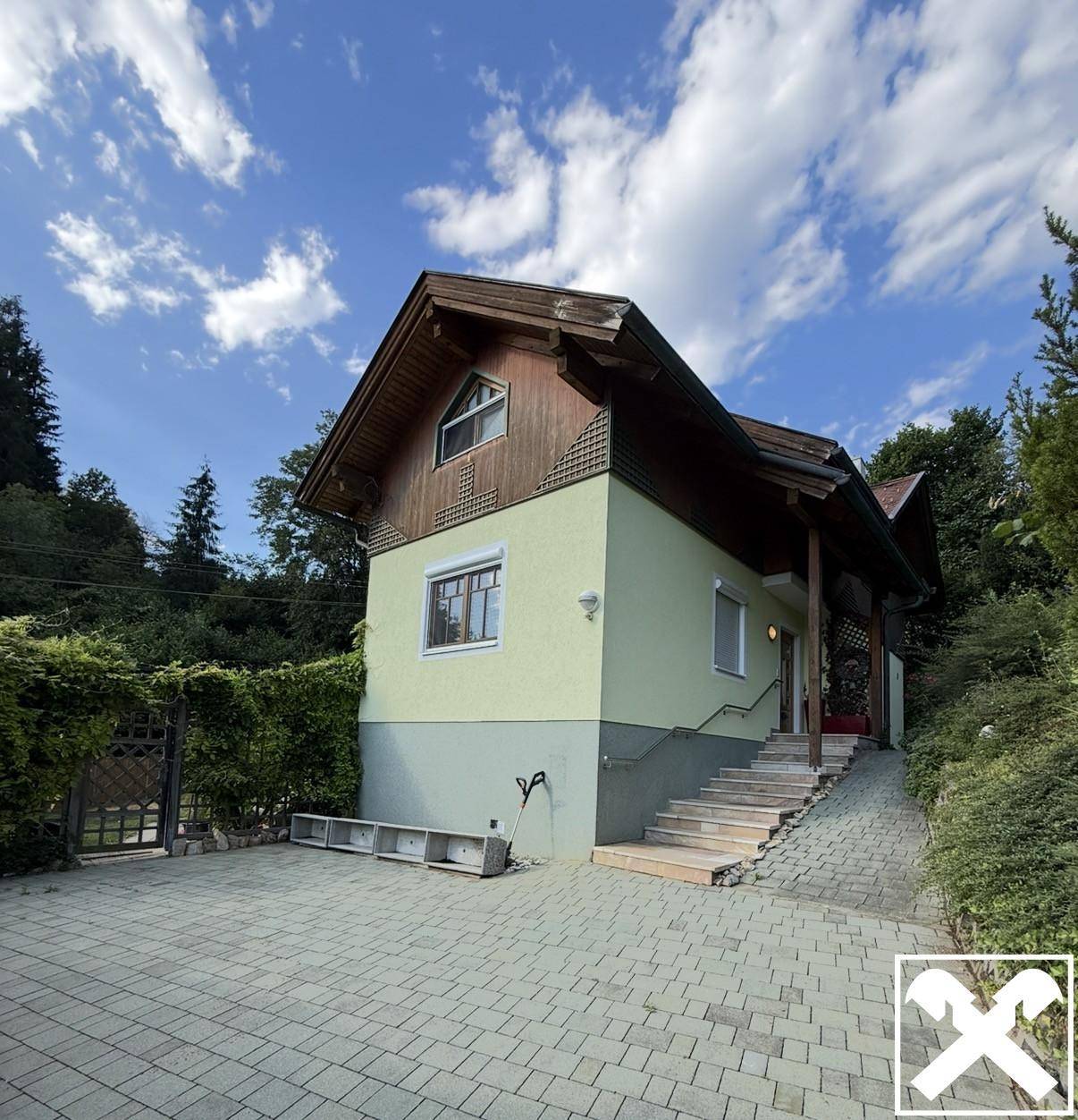 Seitenansicht des Hauses mit gepflasterter Auffahrt und Treppe zum Eingang.
