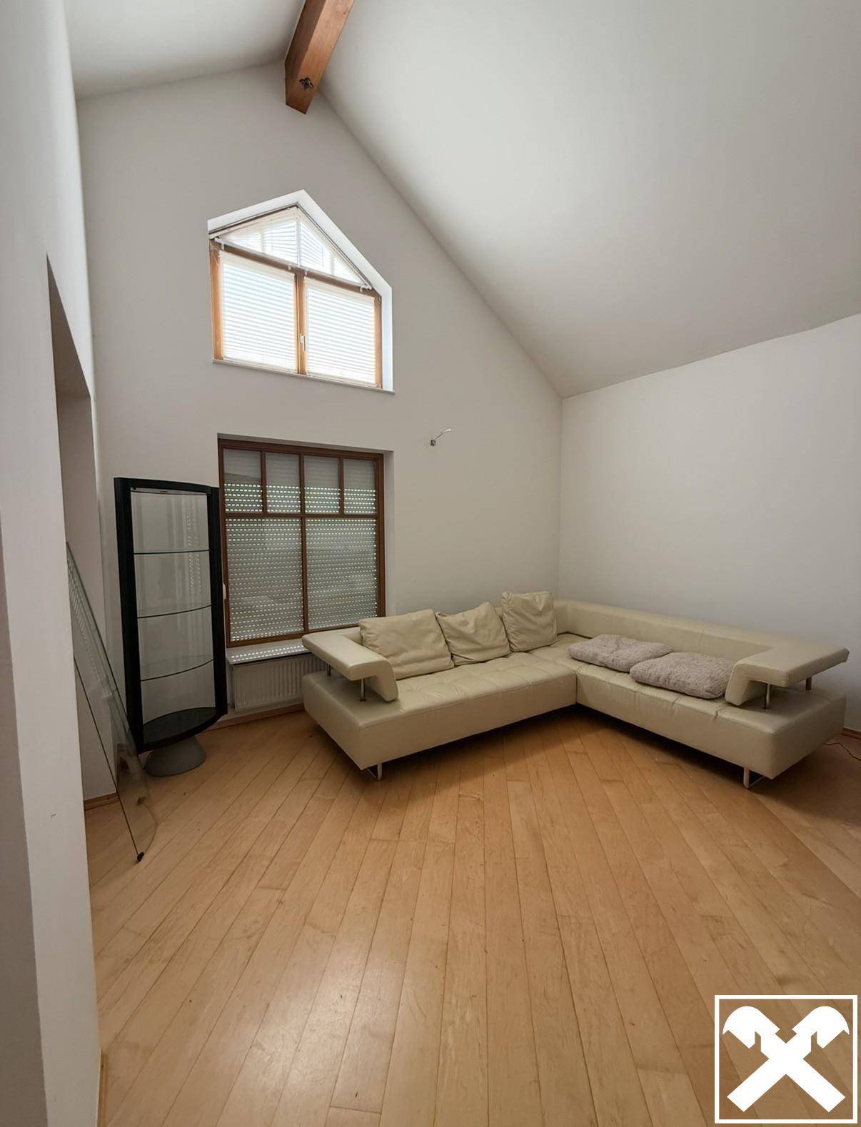 Helles Wohnzimmer mit hohen Decken, Holzbalken und großem Ecksofa.