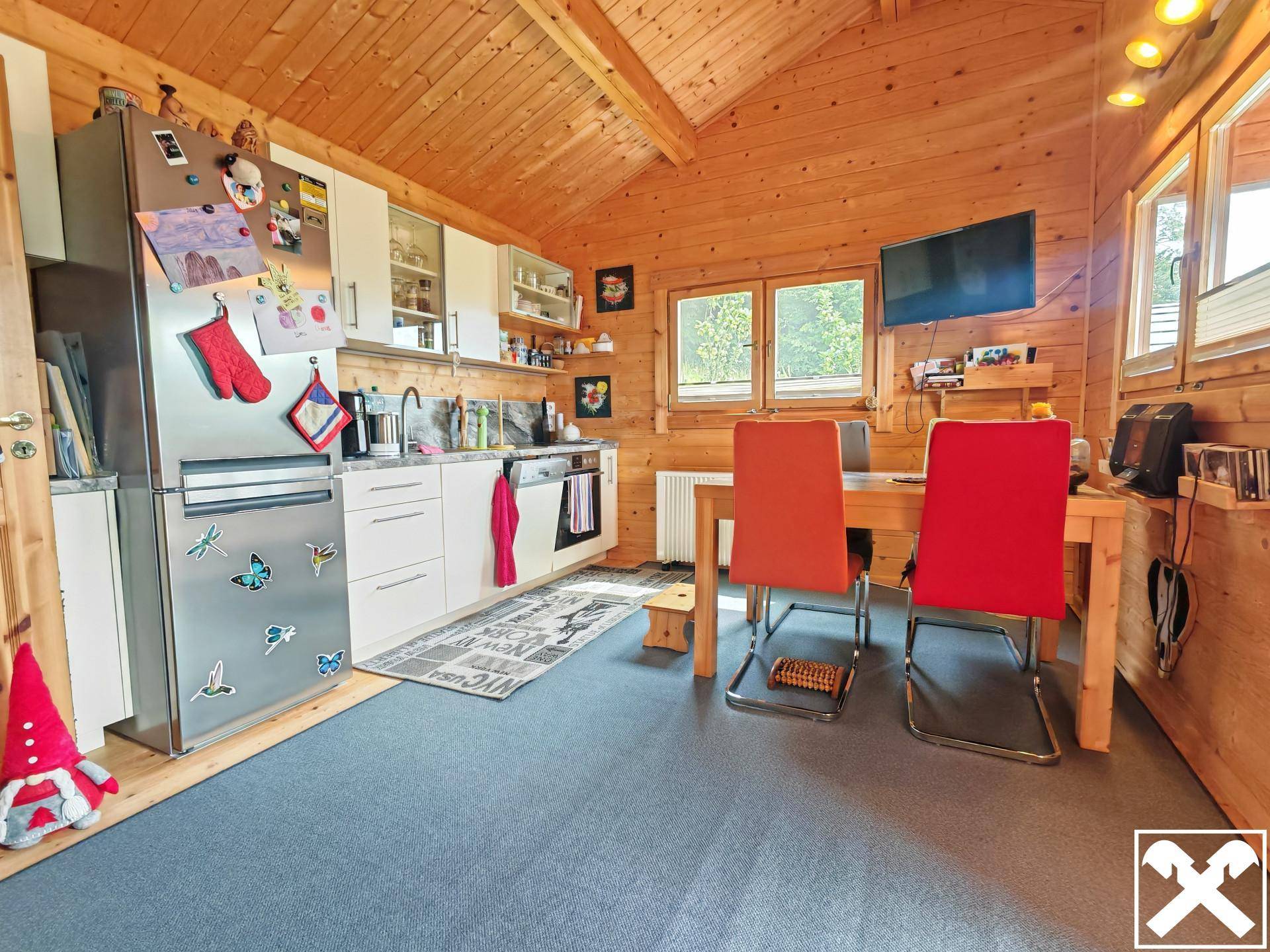 Gemütliche Küche mit Essbereich in einem Holzhaus, ausgestattet mit modernen Geräten und Holzwänden.