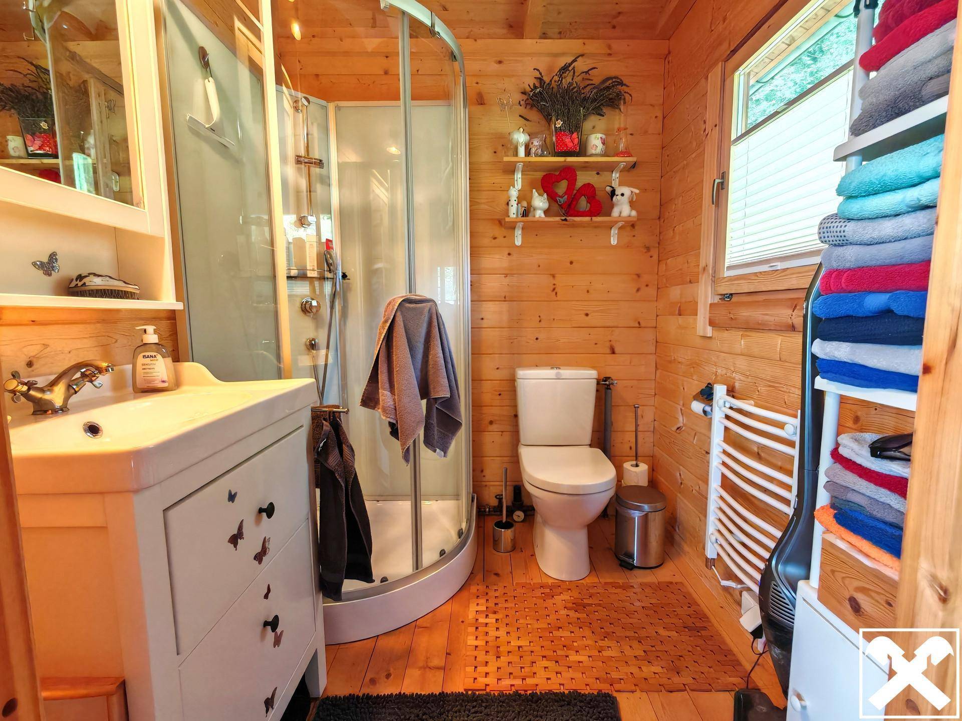 Badezimmer im Holzhaus mit Duschkabine, WC, Waschbecken und beheiztem Handtuchhalter.
