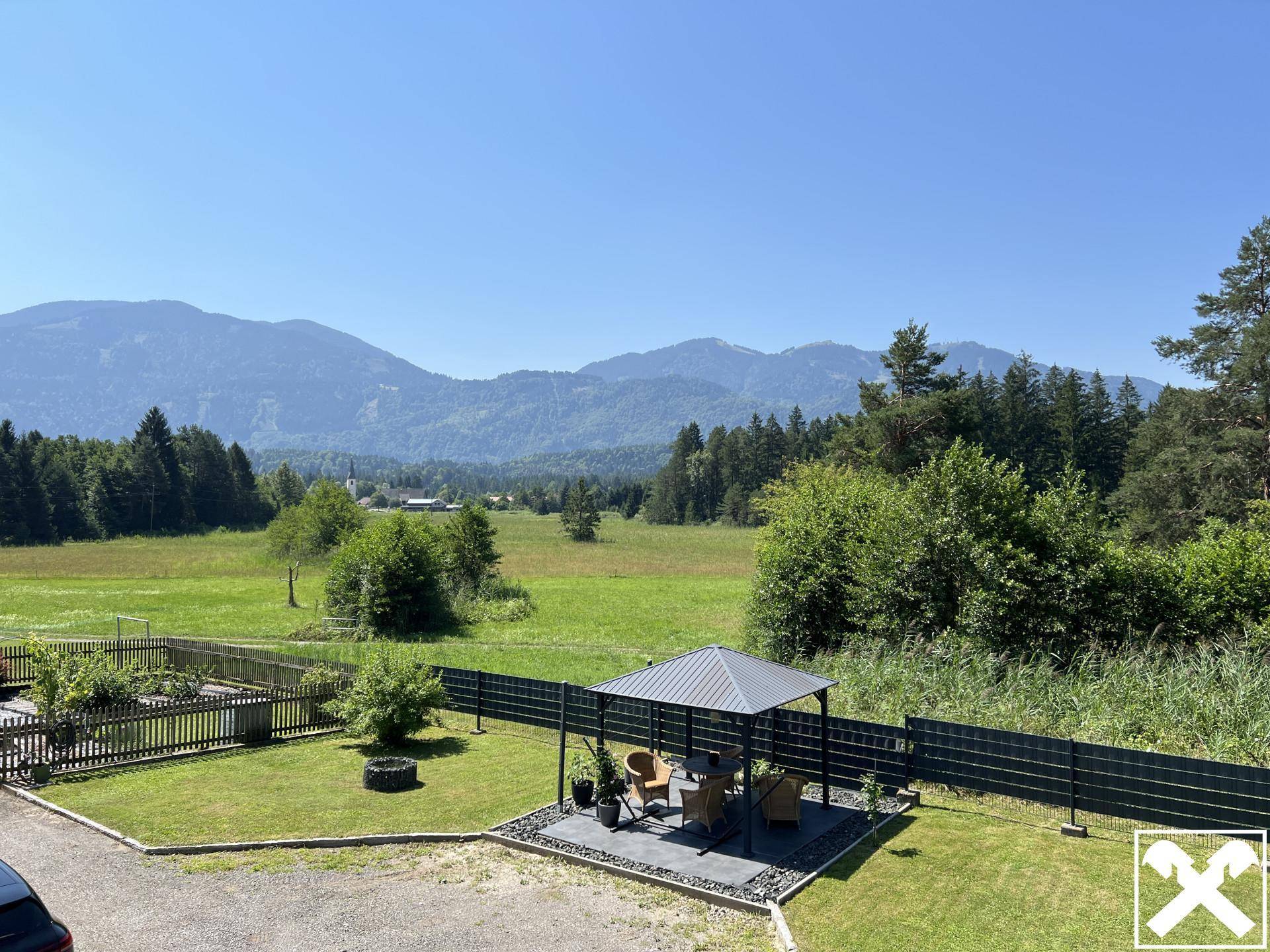 Gepflegter Gartenbereich mit modernem Pavillon und weitem Blick auf die umliegende Berglandschaft.