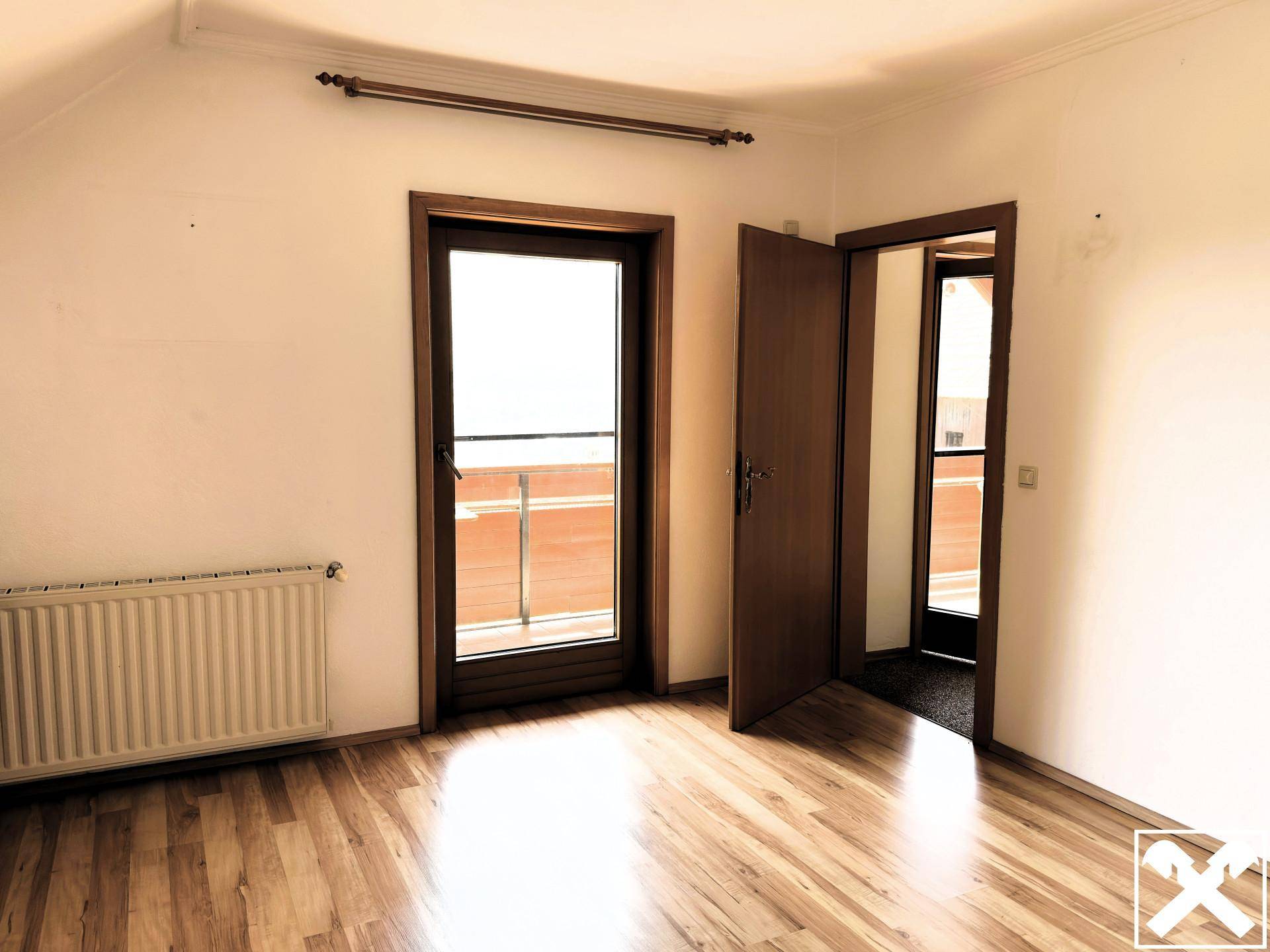 Helles Zimmer mit Holzboden und direktem Zugang zu einem Balkon, ideal als Schlafzimmer.