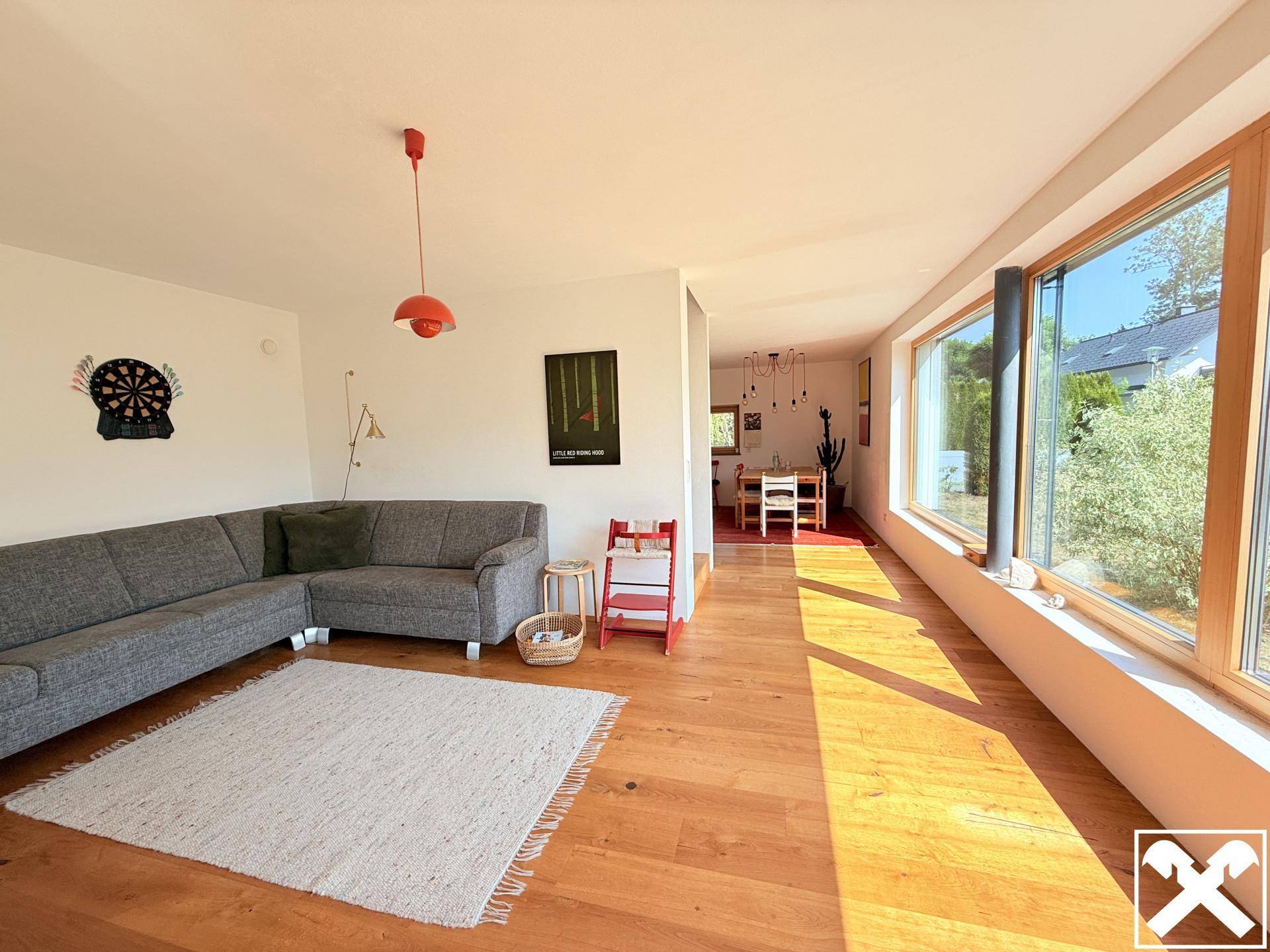 Geräumiger Wohnbereich mit bequemer Couch, Holzboden und großen Fenstern.