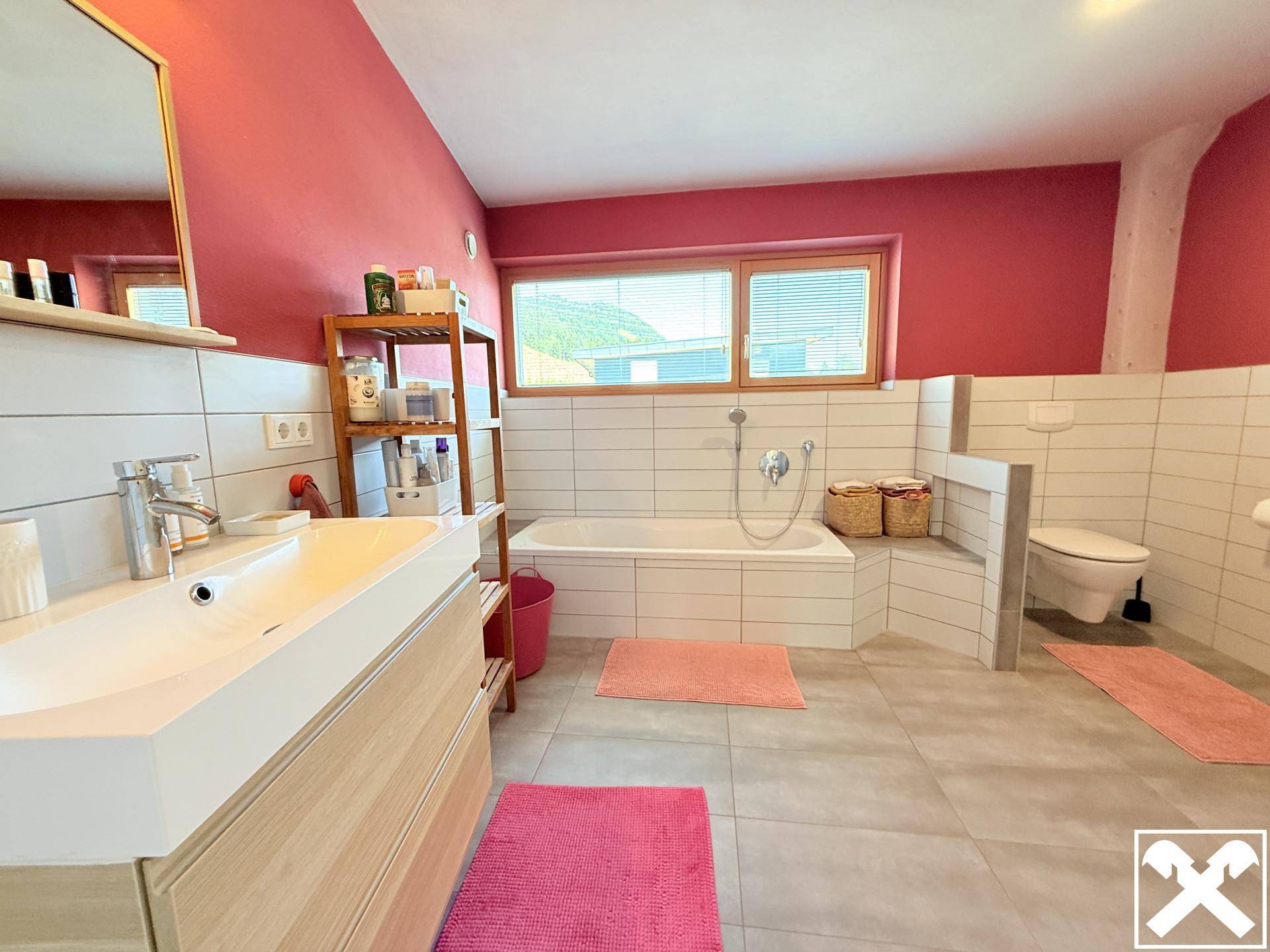 Modernes Badezimmer mit Badewanne, Waschtisch und Fenster in kräftigem Pink.