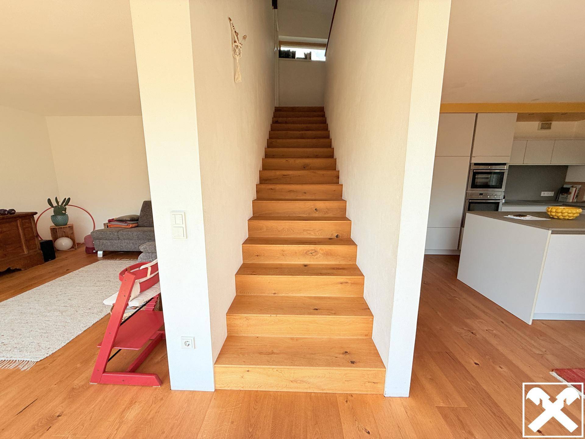 Holztreppe verbindet die Etagen in einem hellen, offen gestalteten Wohnbereich.