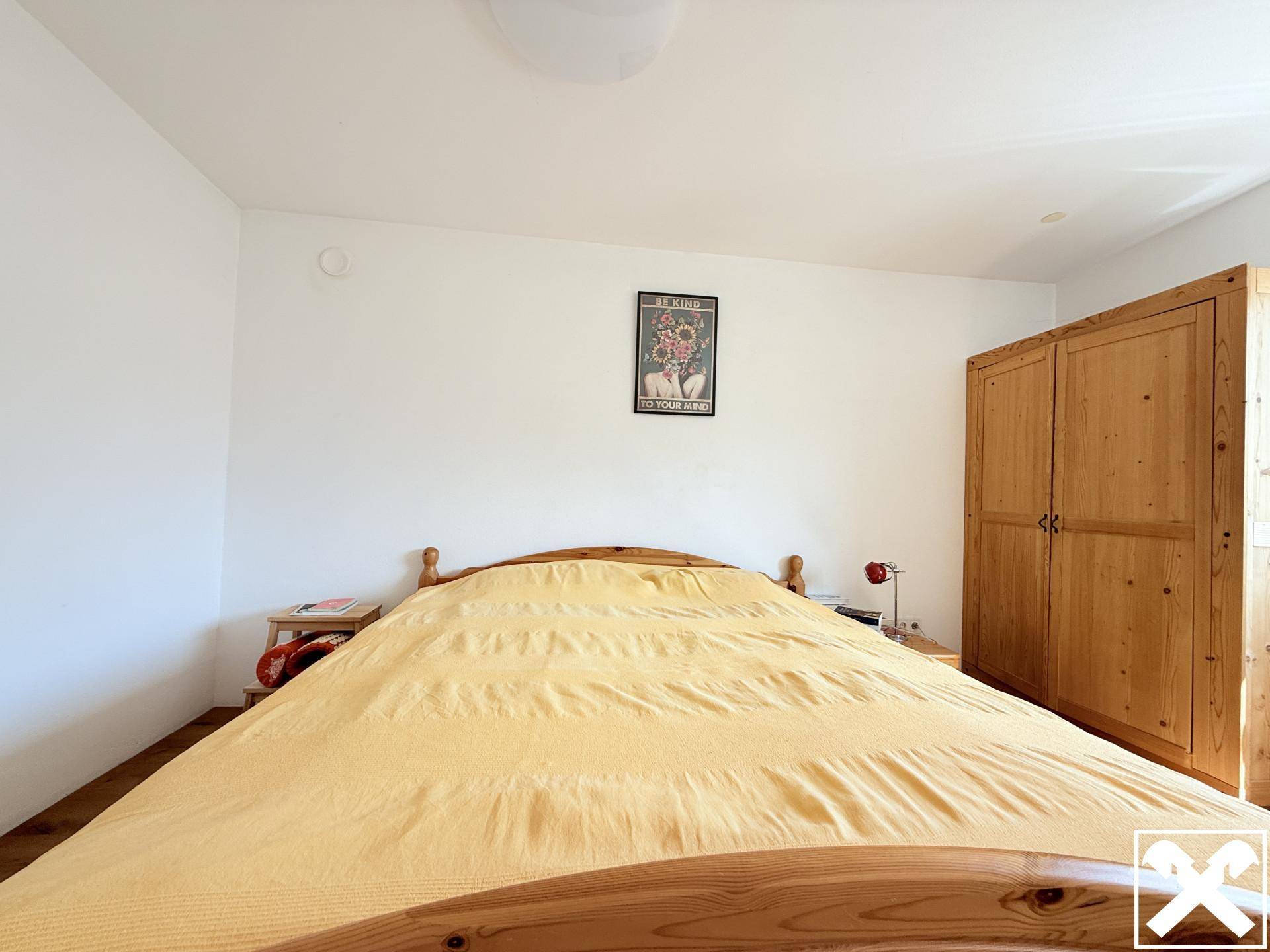 Gemütliches Schlafzimmer mit Holzbett, Holzschrank und hellem Holzboden.