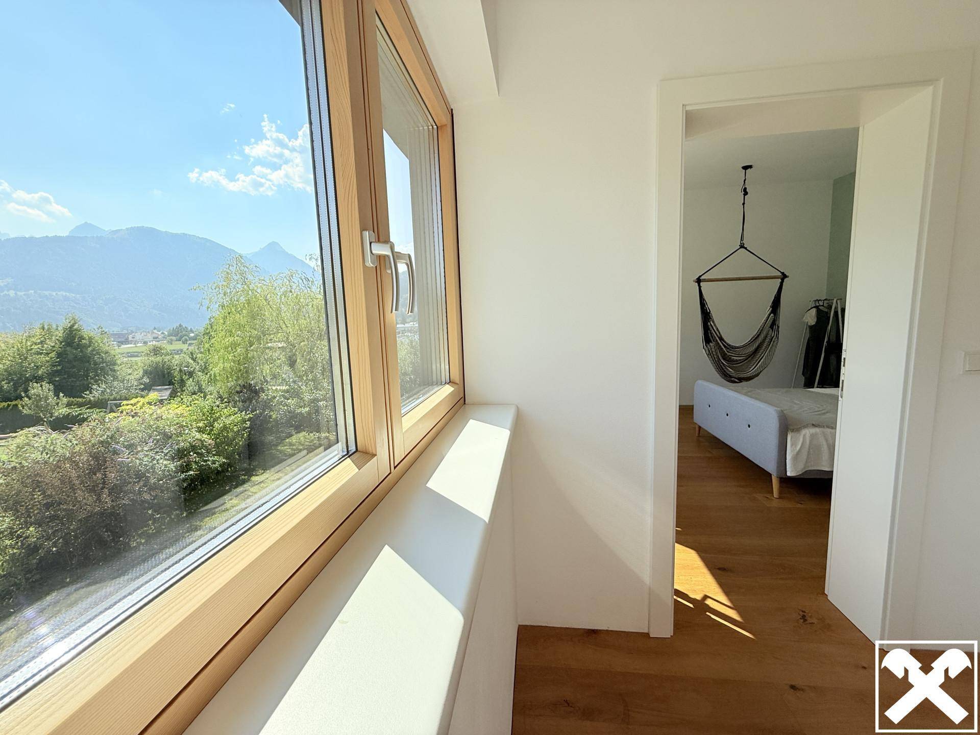Heller Flur mit großem Fenster und weitem Blick auf die grüne Berglandschaft.