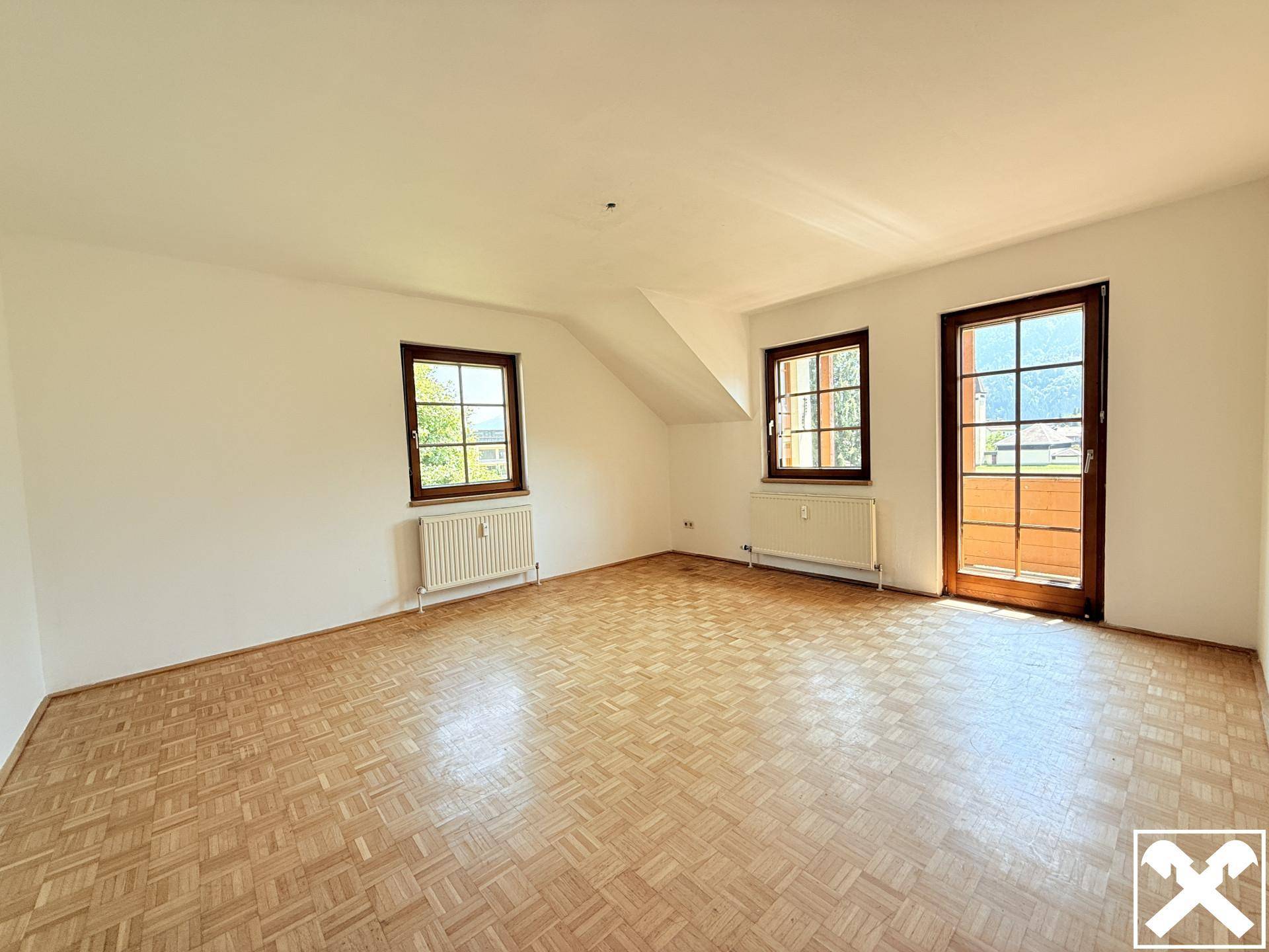 Heller Raum mit Parkettboden, Dachschräge und Zugang zu einem Balkon oder einer Loggia.