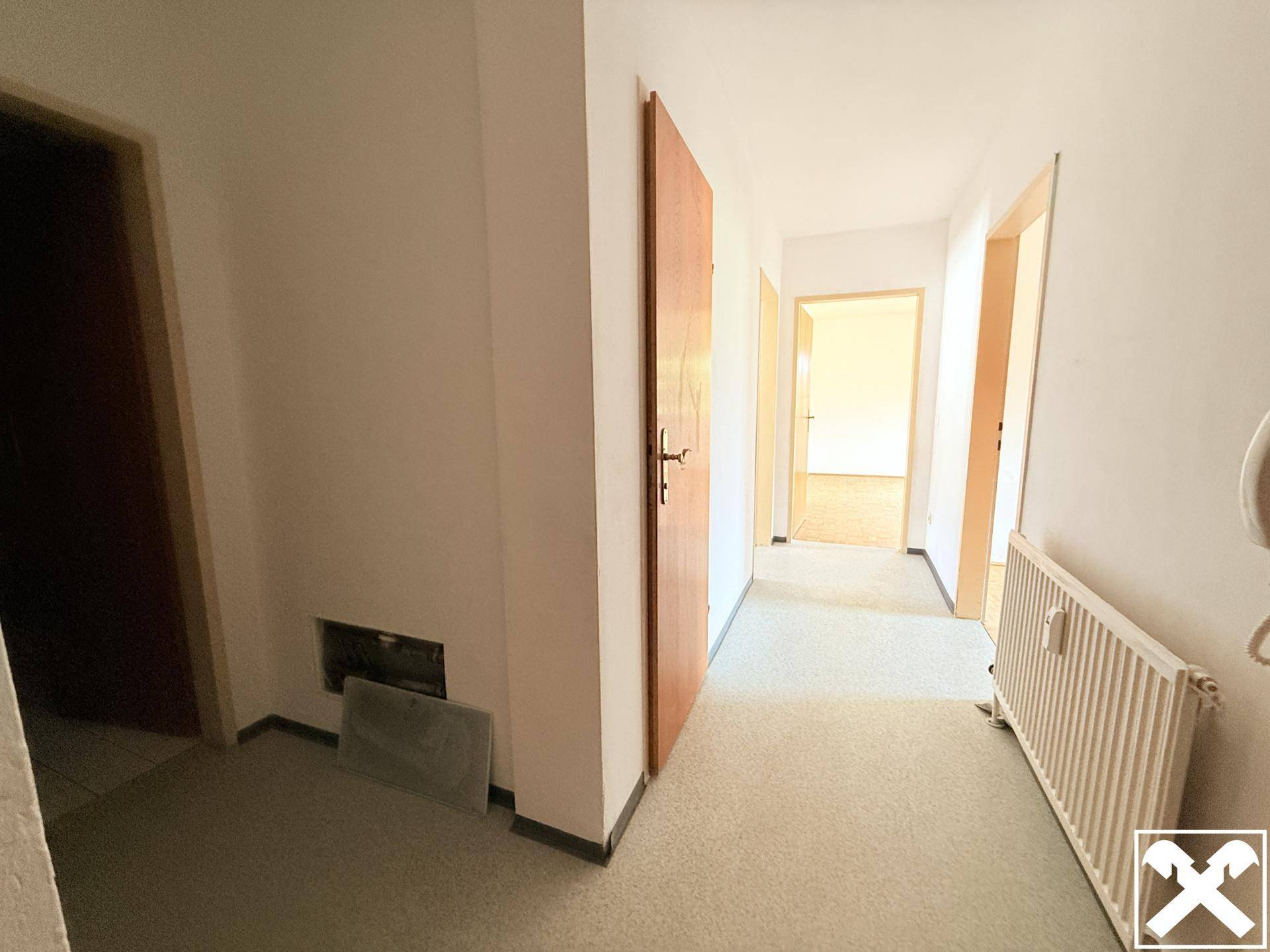 Heller Flur mit Teppichboden und mehreren Türen, der zu verschiedenen Räumen führt.