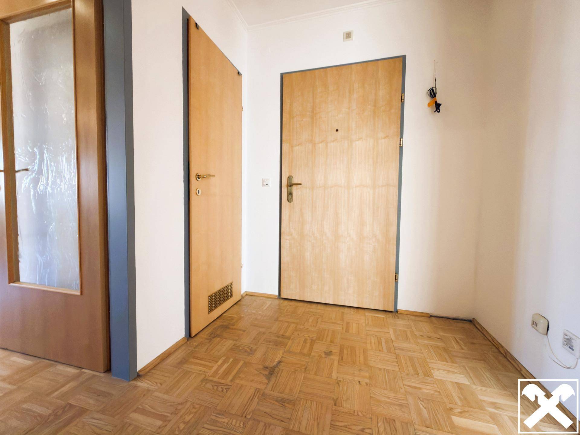 Eingangsbereich der Wohnung mit Parkettboden und Holztüren.