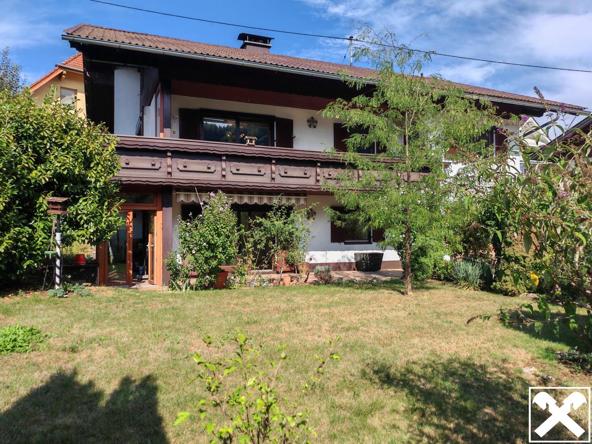 Rückansicht des Hauses mit Gartenbereich und Terrasse, umgeben von grüner Natur.