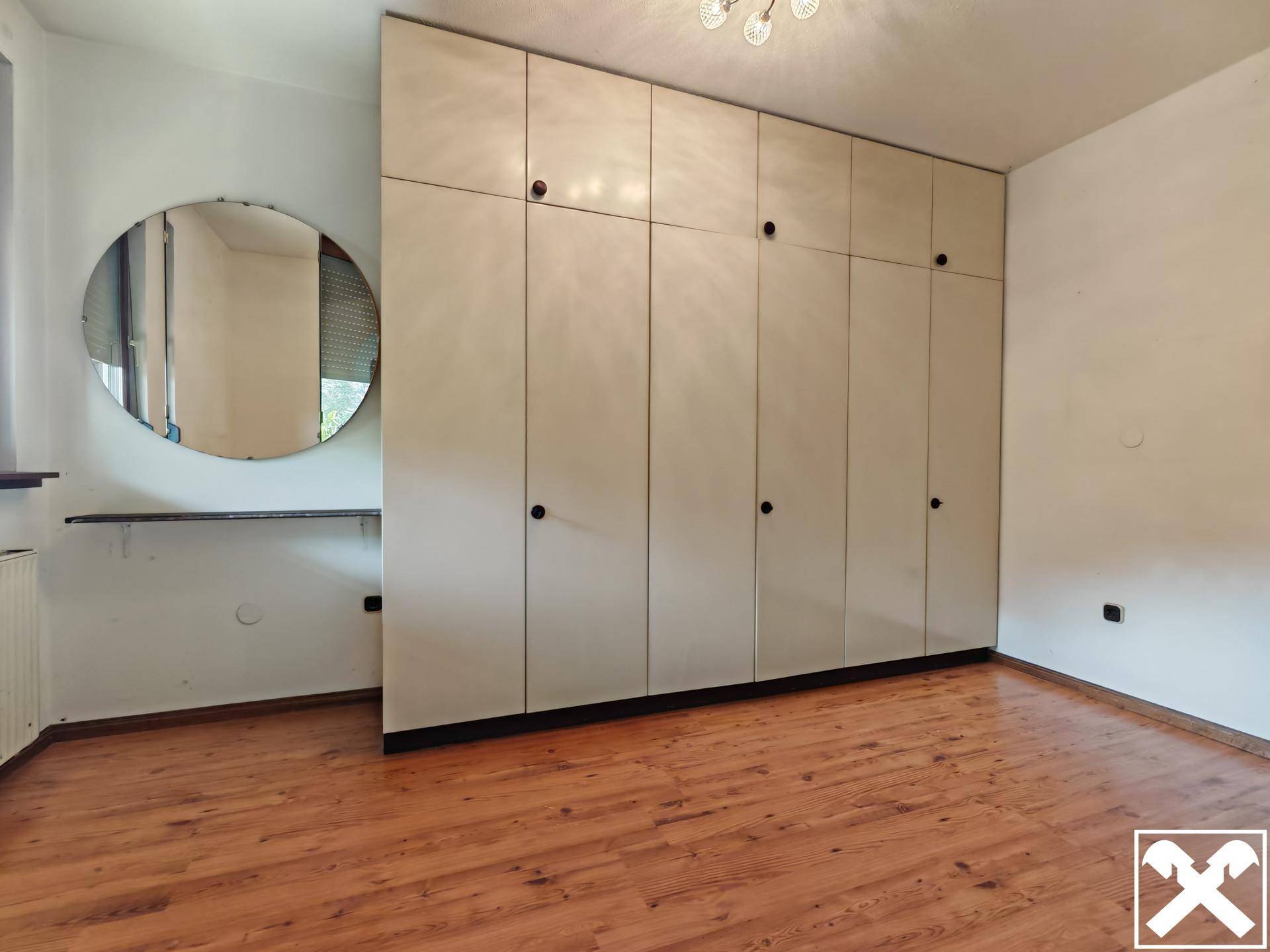 Schlafzimmer mit großem Einbauschrank und Laminatboden, bietet viel Stauraum.