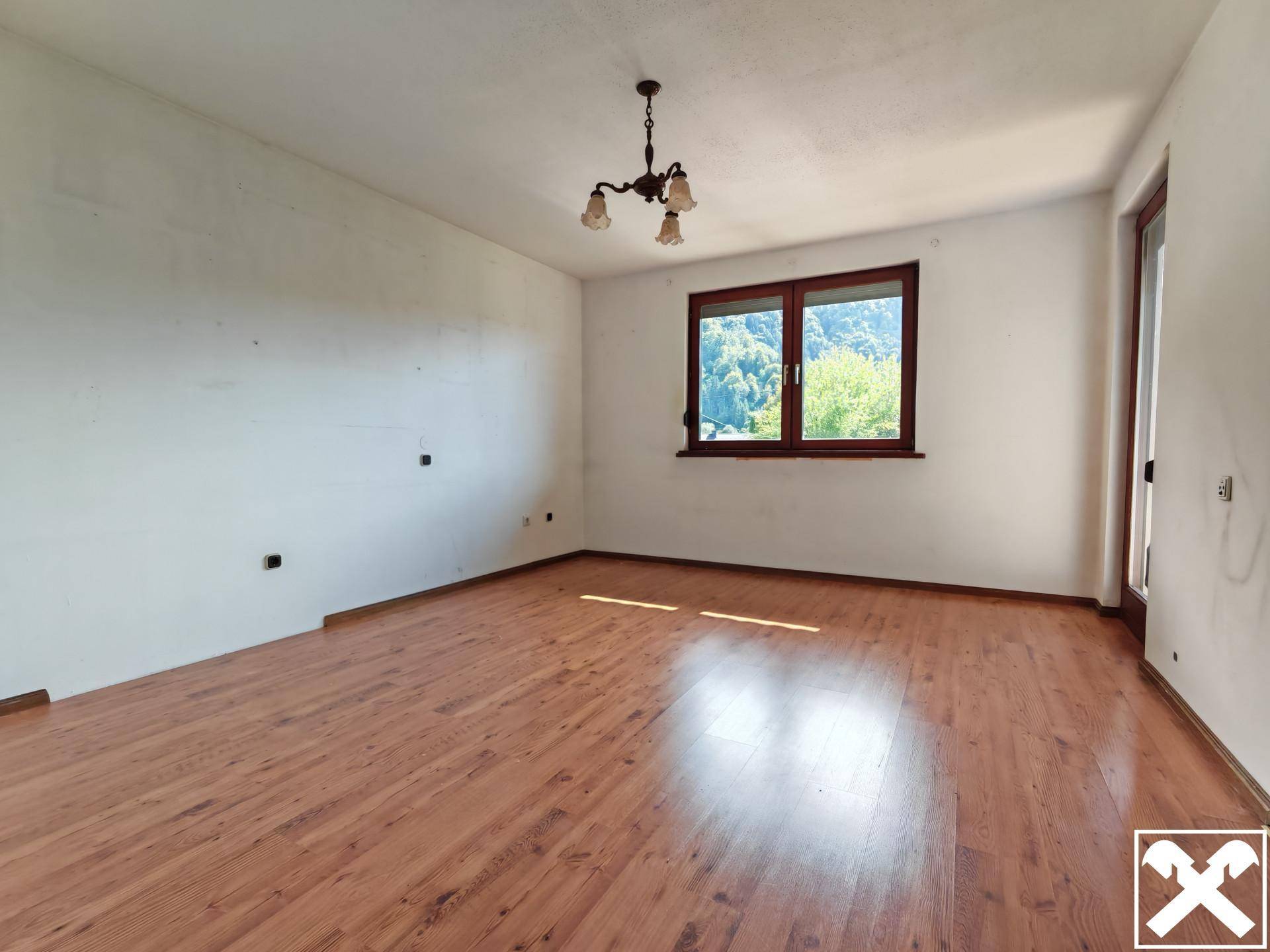 Geräumiges Schlafzimmer mit Laminatboden und großem Fenster, das viel Licht hereinlässt.