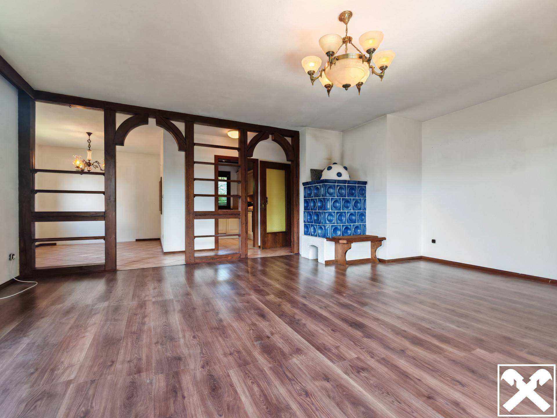 Geräumiges Wohnzimmer mit Laminatboden und einem traditionellen blauen Kachelofen.
